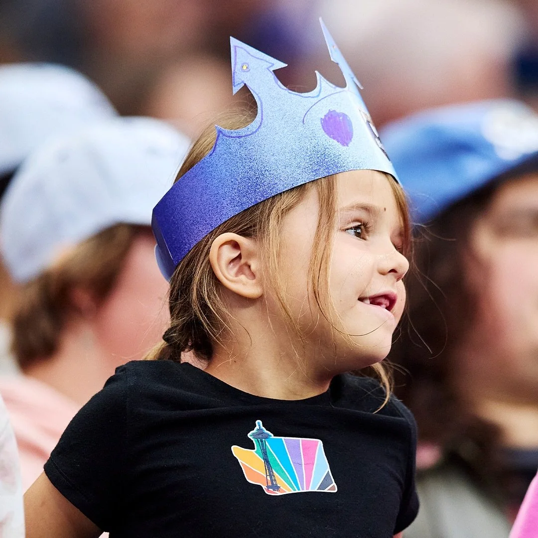 Small child with a crown smiling at a Reign FC match
