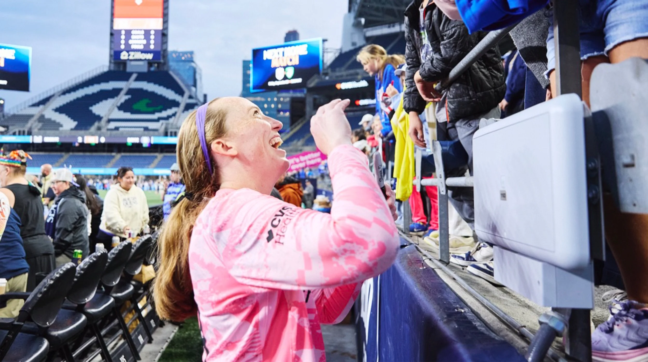 Cassie Miller smiling while signing items for fans at Lumen Field