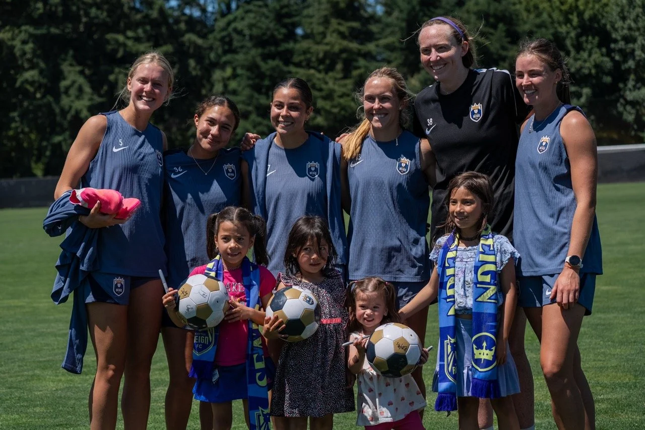Reign FC players posing with children holding soccer balls