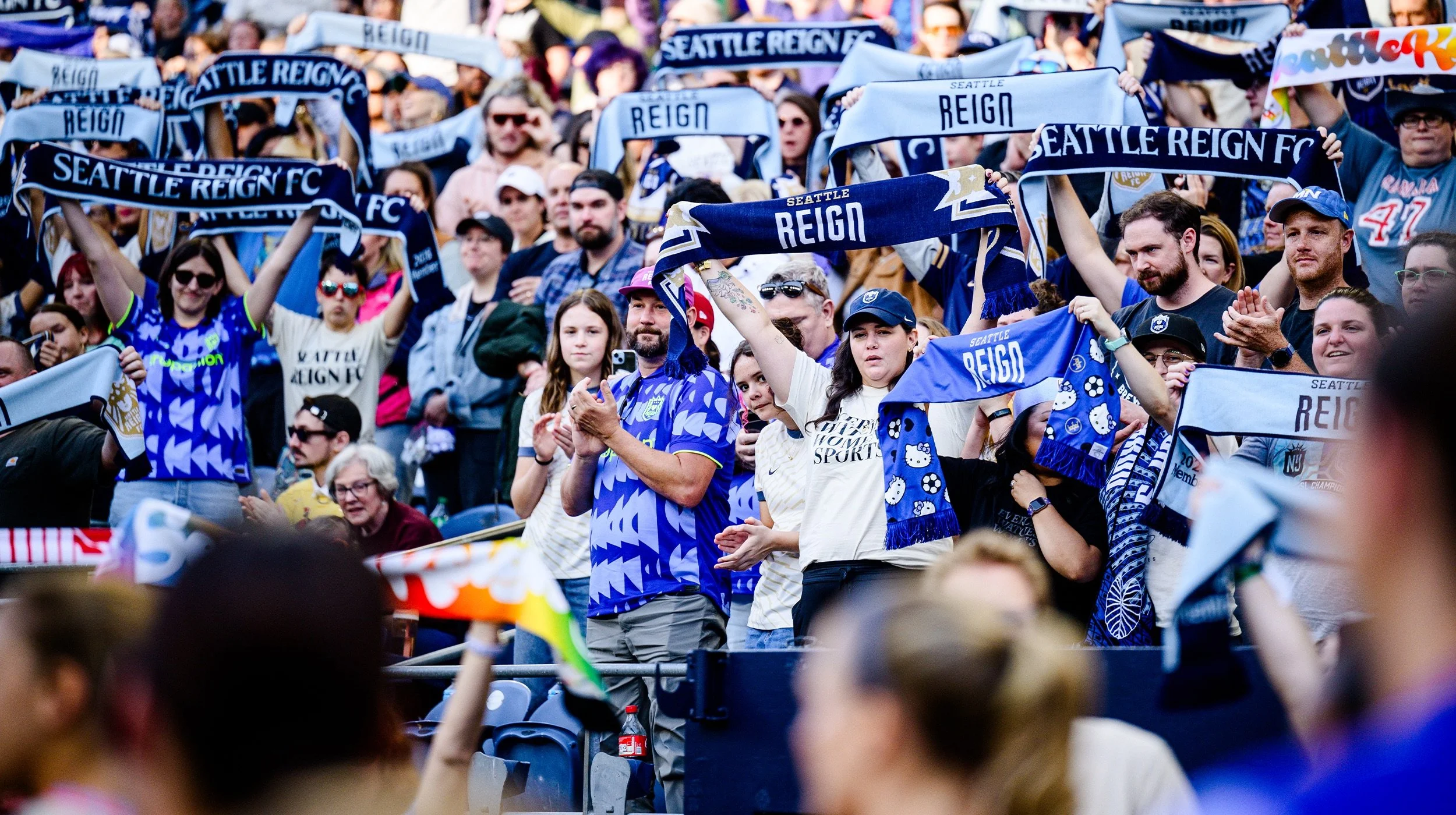 Reign FC fans in lumen field holding up Reign FC scarves