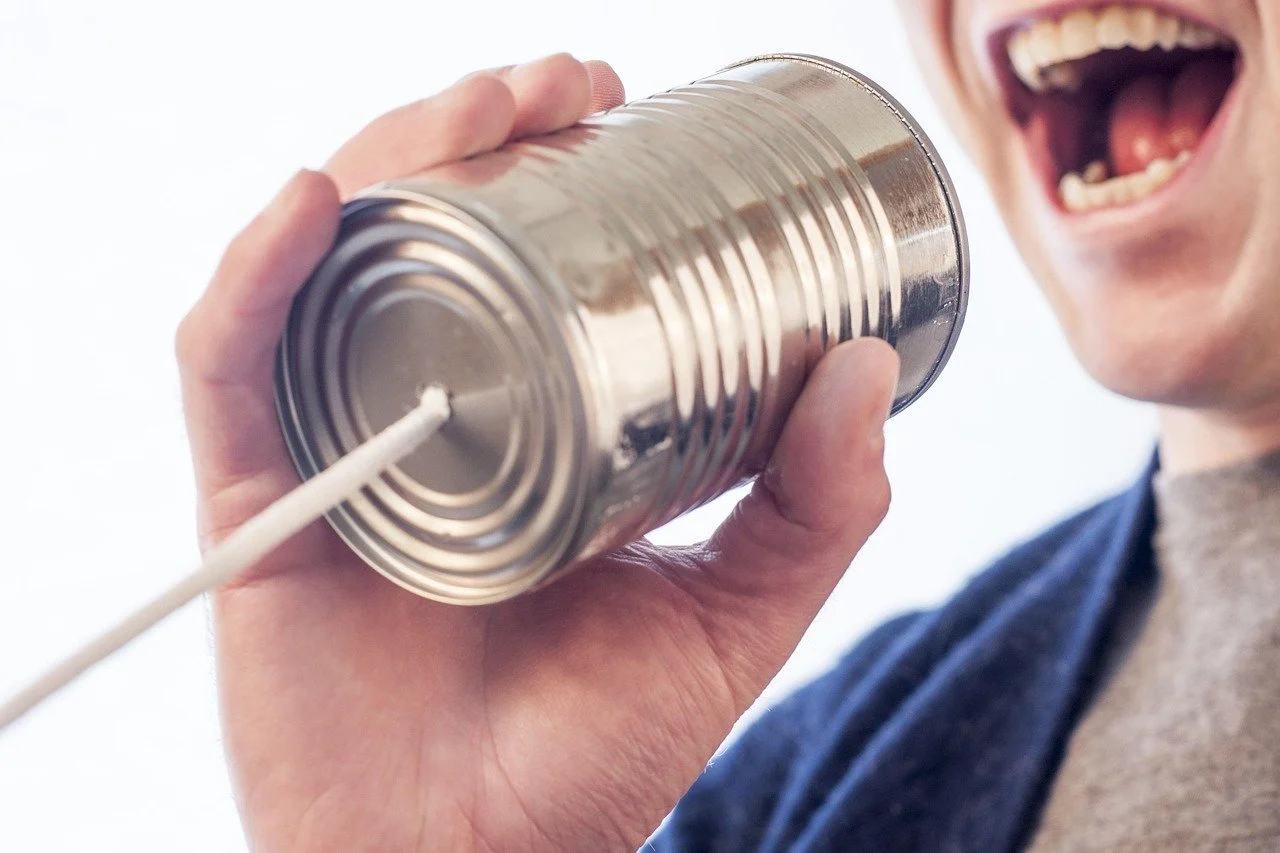 Man shouting into a telephone made of a tin can and string.