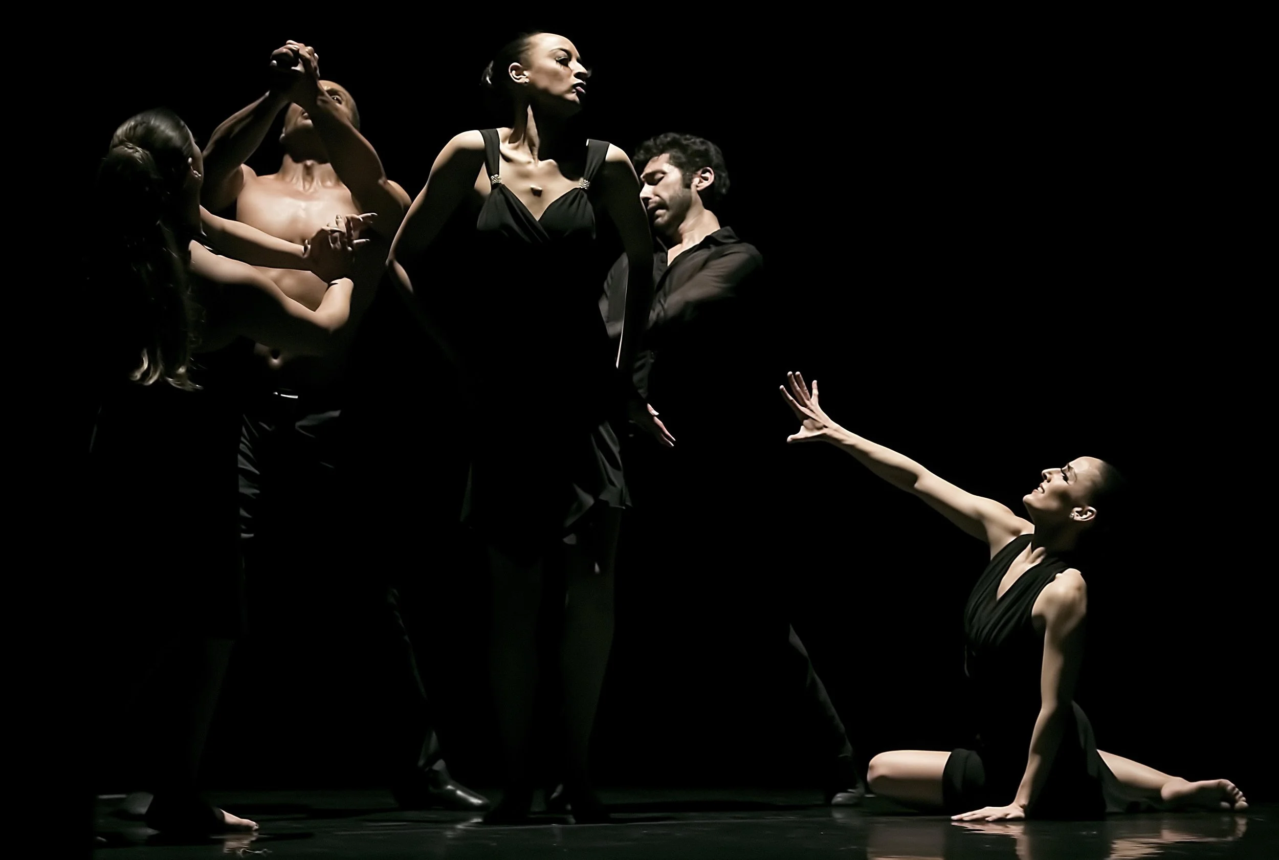 Five dancers in a dramatic pose on stage