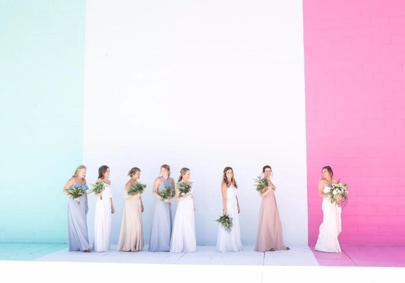 A bride and her bridal party poses in front of the large outdoor color wall in Southwest Michigan at Wind and James