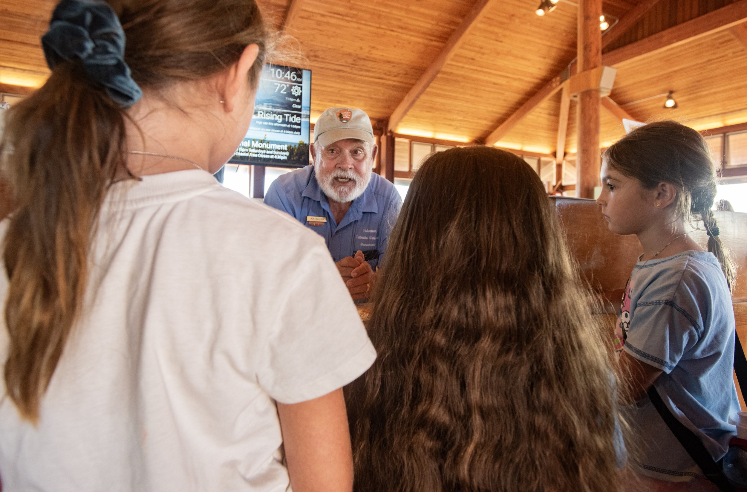 Visitors receive their Jr. Ranger booklets from Visitor Center Information Desk Volunteer.