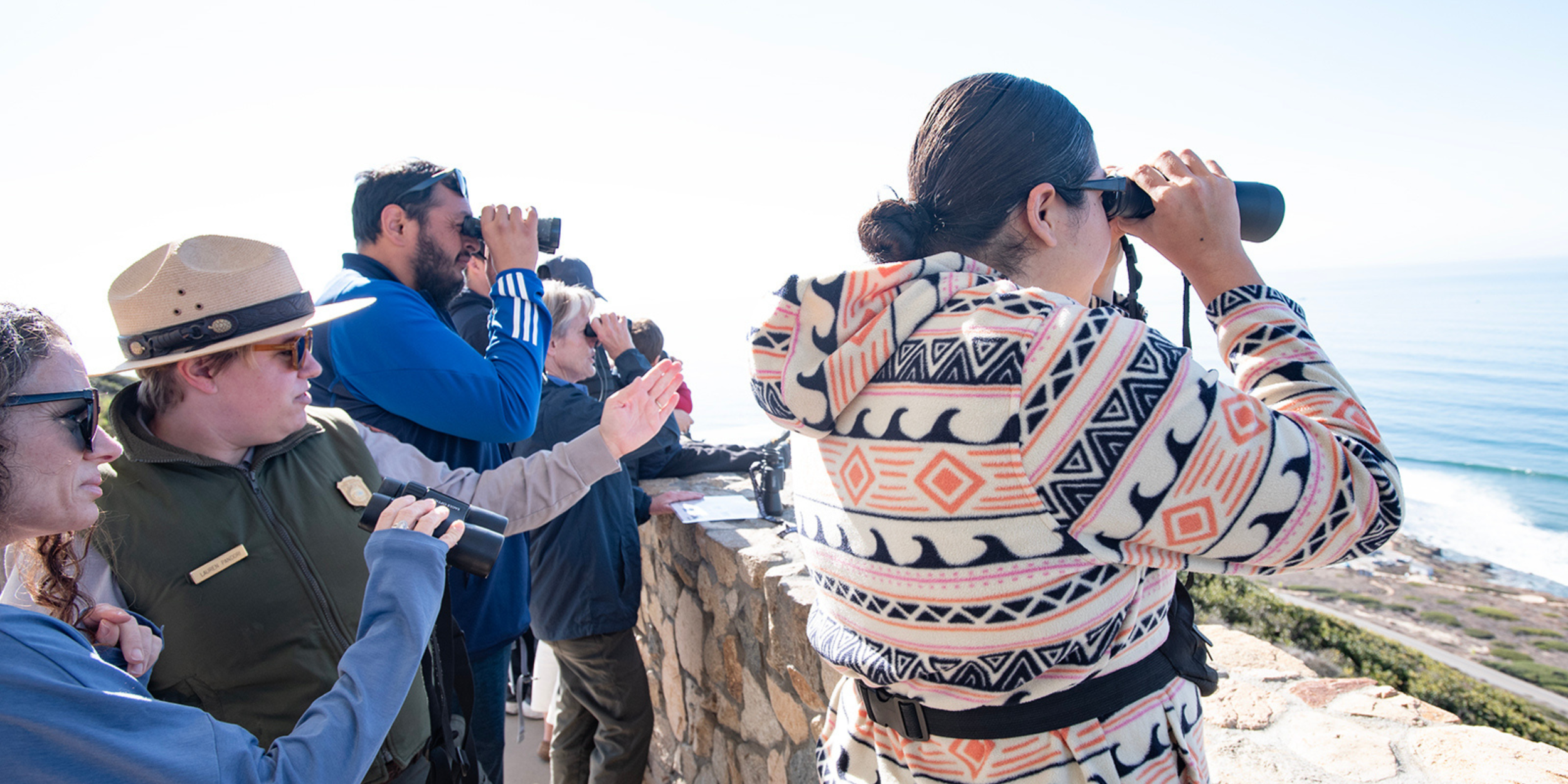 NPS Ranger helping visitors spot grey whales with binoculars during whale watch weekend