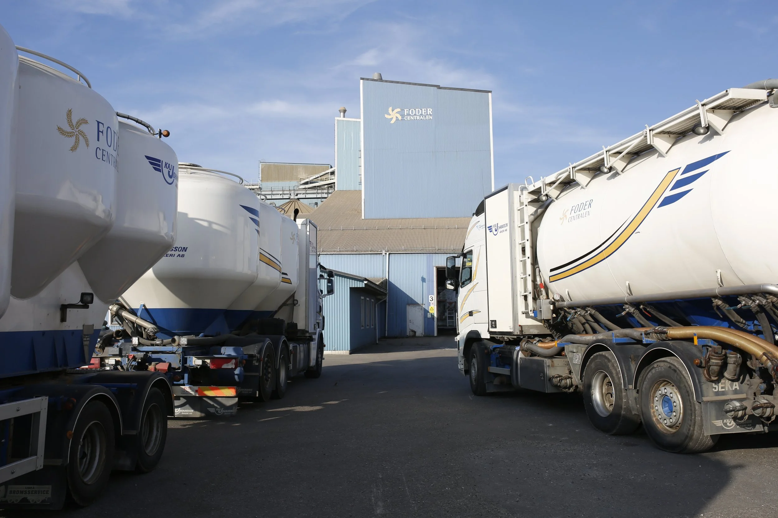 Vita tankbilar parkerade framför en industribyggnad.