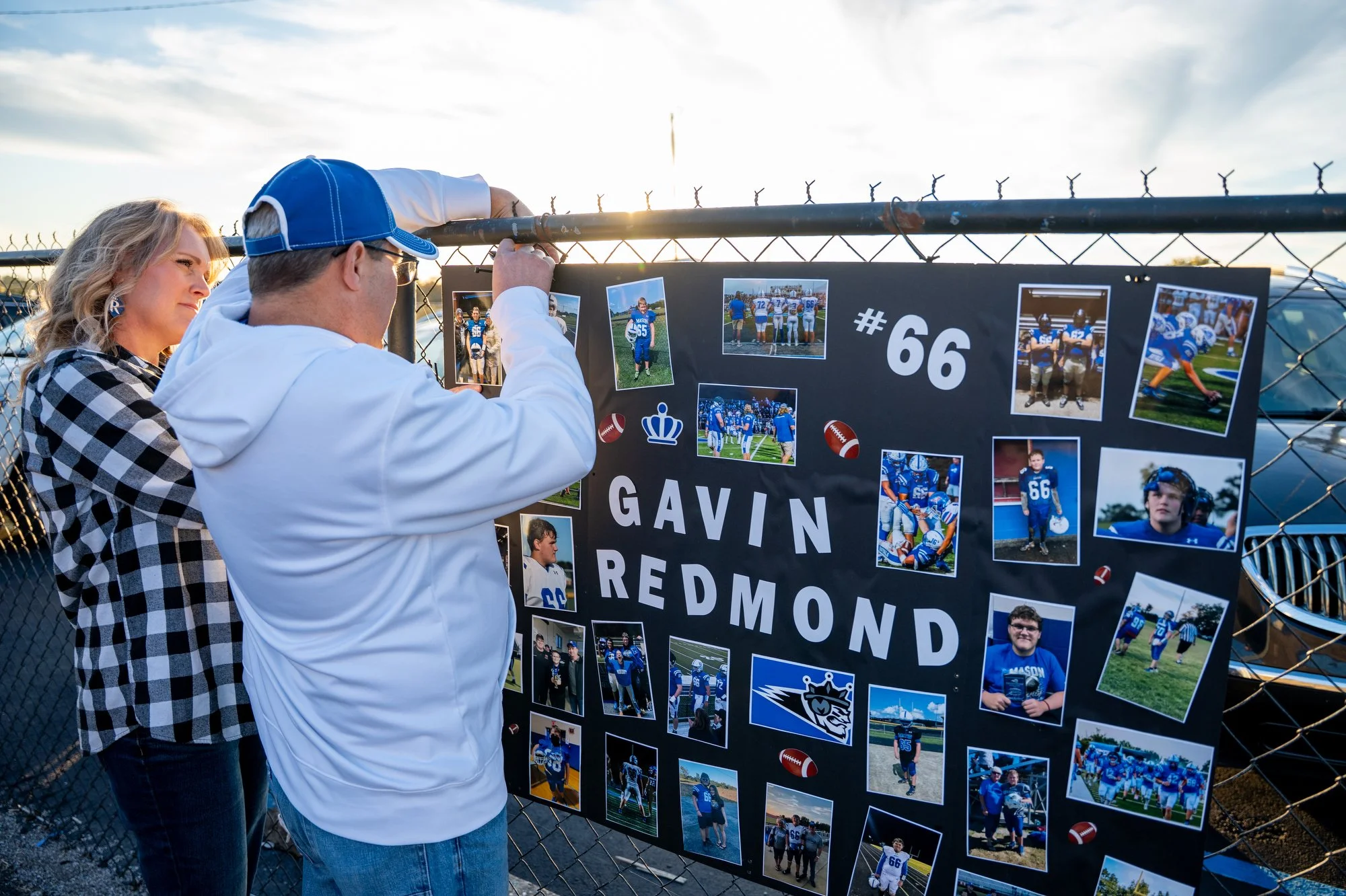 Melinda and Chris Redmond hang up Gavin’s celebratory senior night poster before the game kicked off. 