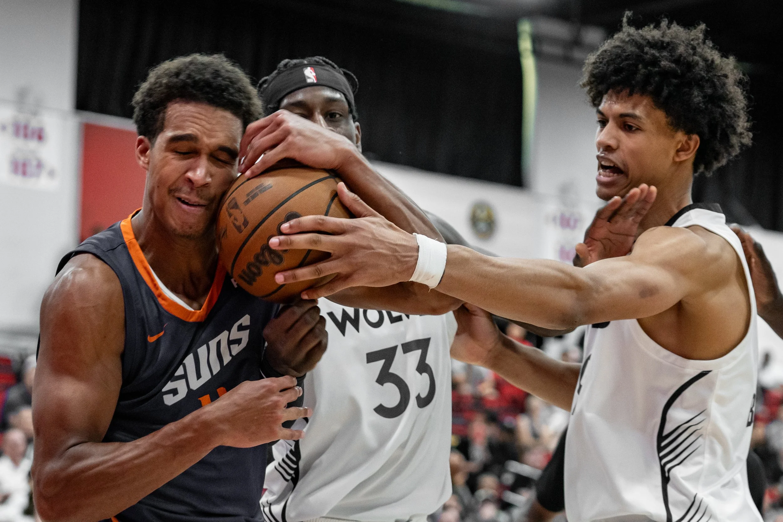 Phoenix Sun forward Oso Ighodaro (4) attempts to protect a rebound from Minnesota Timberwolves forwards Leonard Miller (33) and Joan Beringer (19) during an NBA 2K26 Summer League matchup in Las Vegas on July 16, 2025. The Minnesota Timberwolves defe