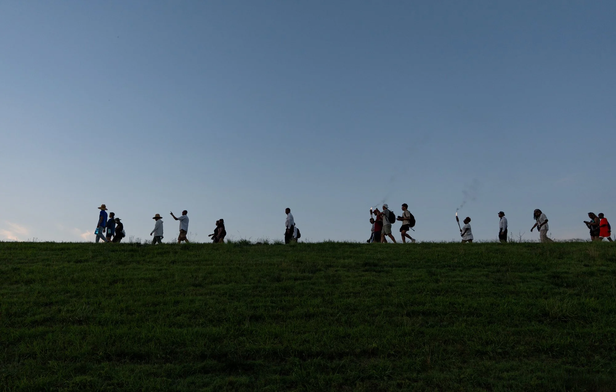 Participants walk while carrying torches along the James River.