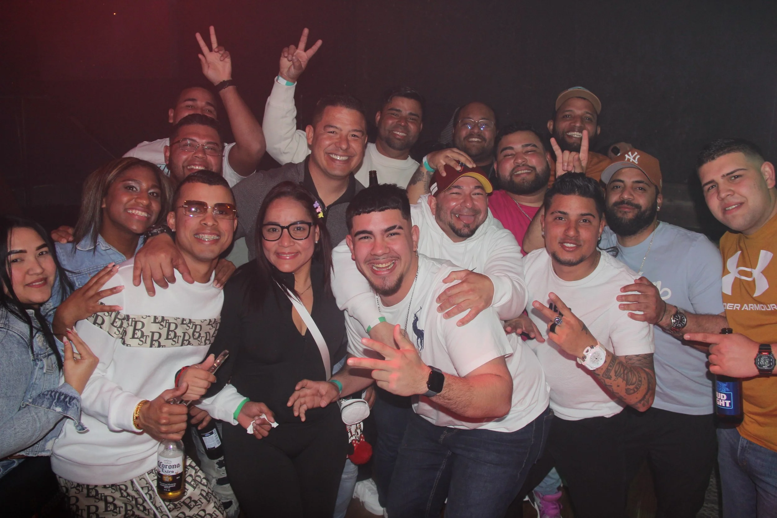 Group of people smiling and posing for a photo at a social event, some holding drinks.