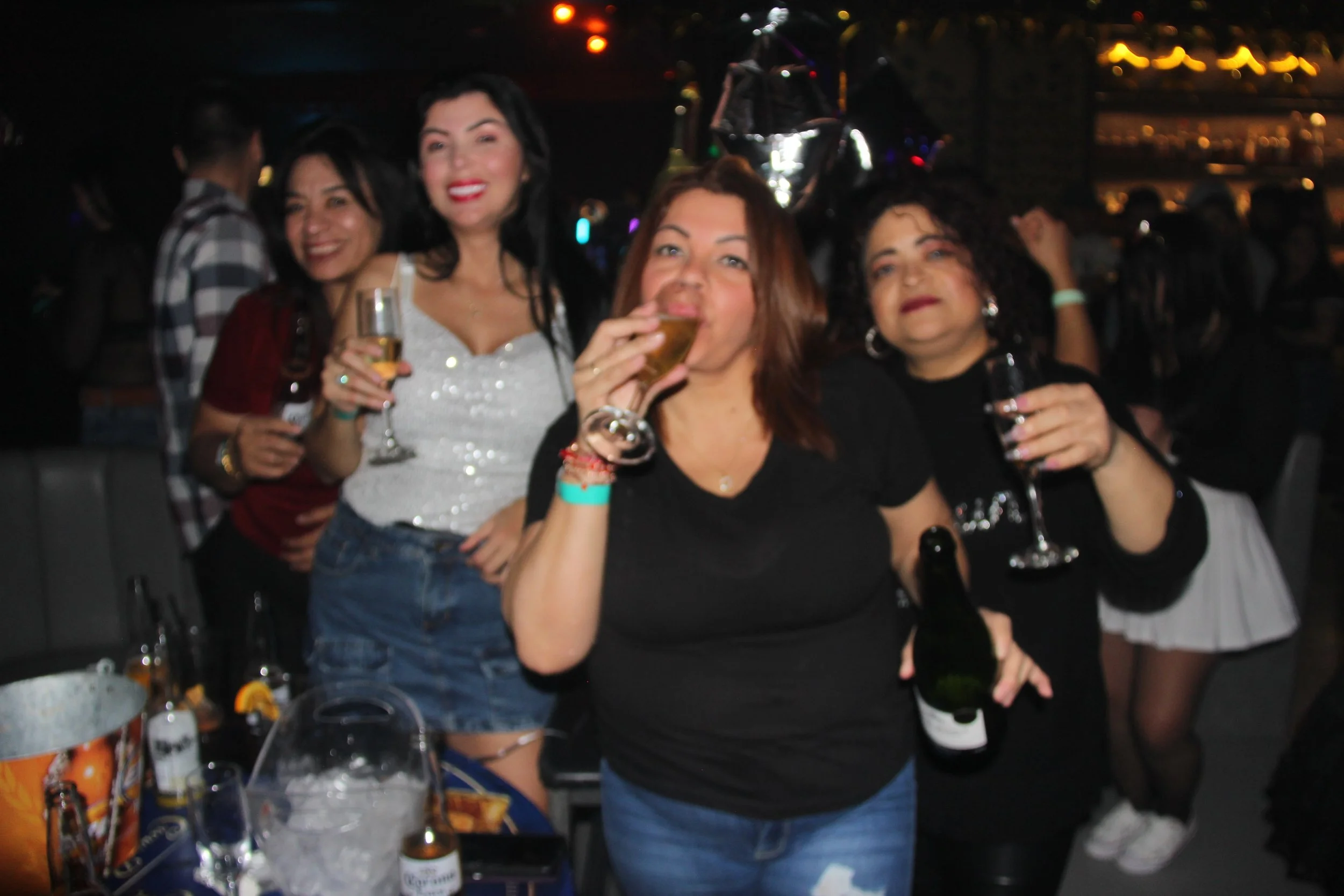 Group of women smiling and holding drinks at a party.