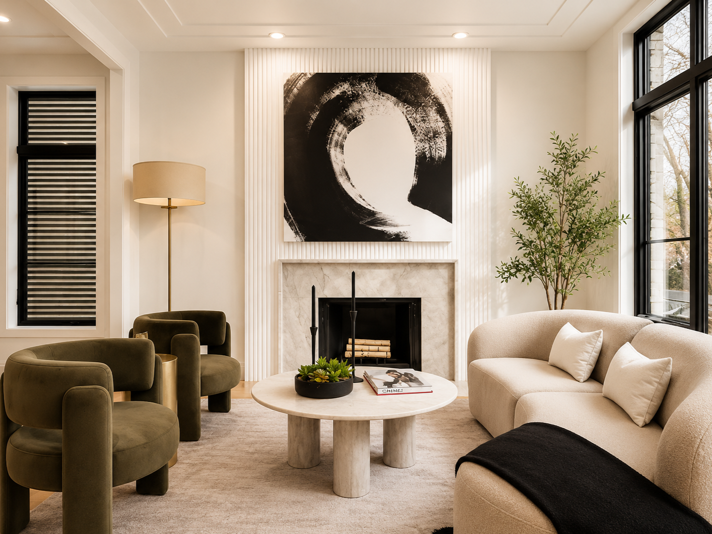 Modern living room with a beige sofa, green armchairs, a round marble table, and a fireplace with abstract black and white artwork above. Large windows with black frames, a tall floor lamp, and a potted plant add to the decor.