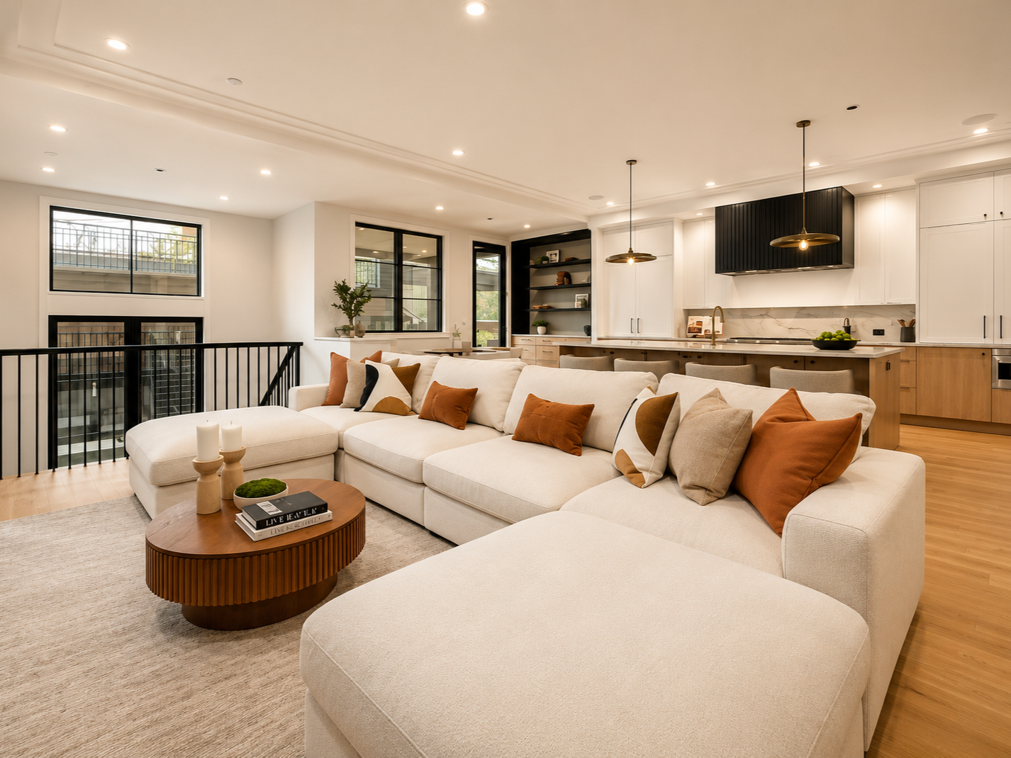 Living room with a large white sectional sofa, cushions, coffee table, and open kitchen in background.