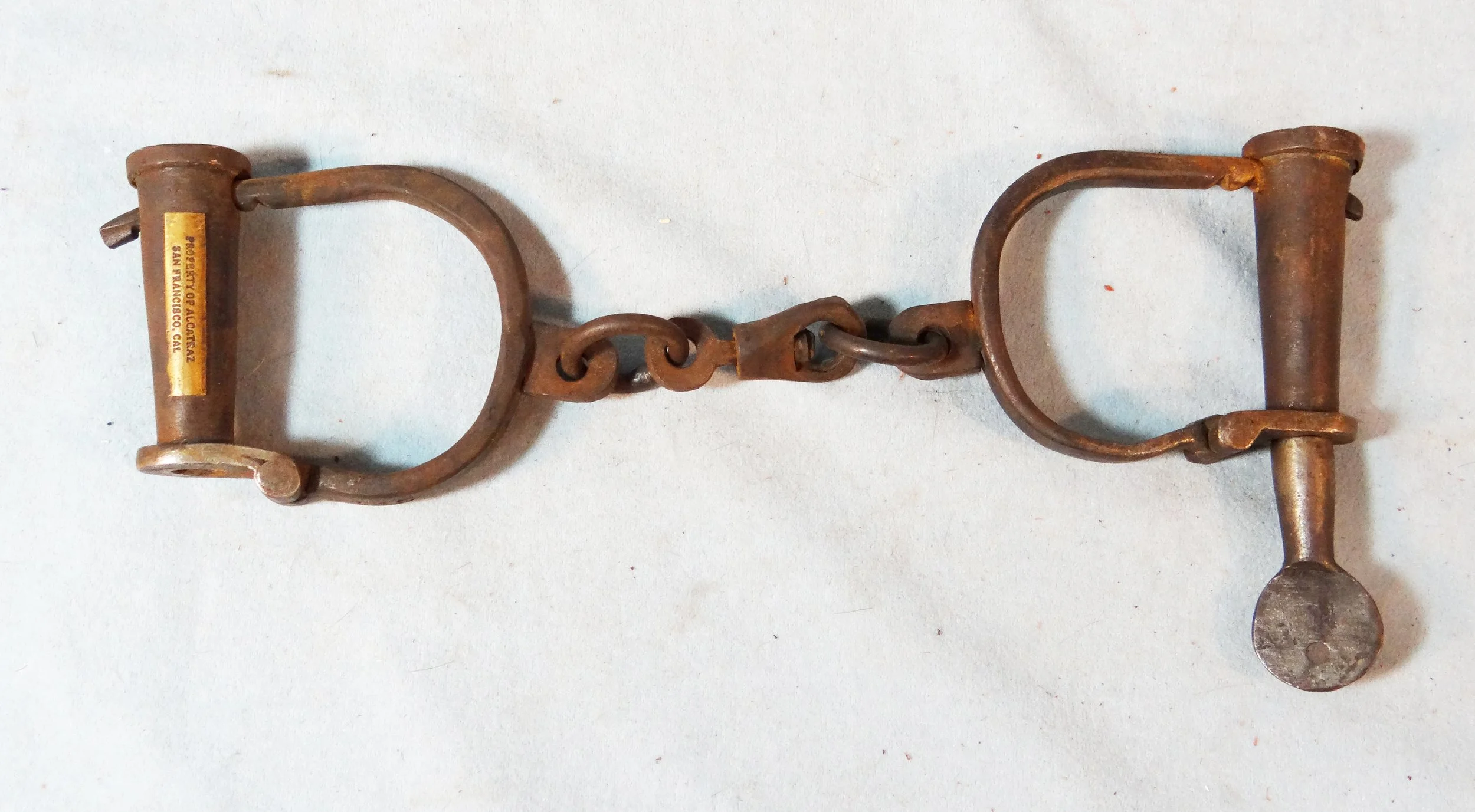 Vintage handcuffs with key, marked Property of Alcatraz, San Francisco, Cal, 135C stamped on key
