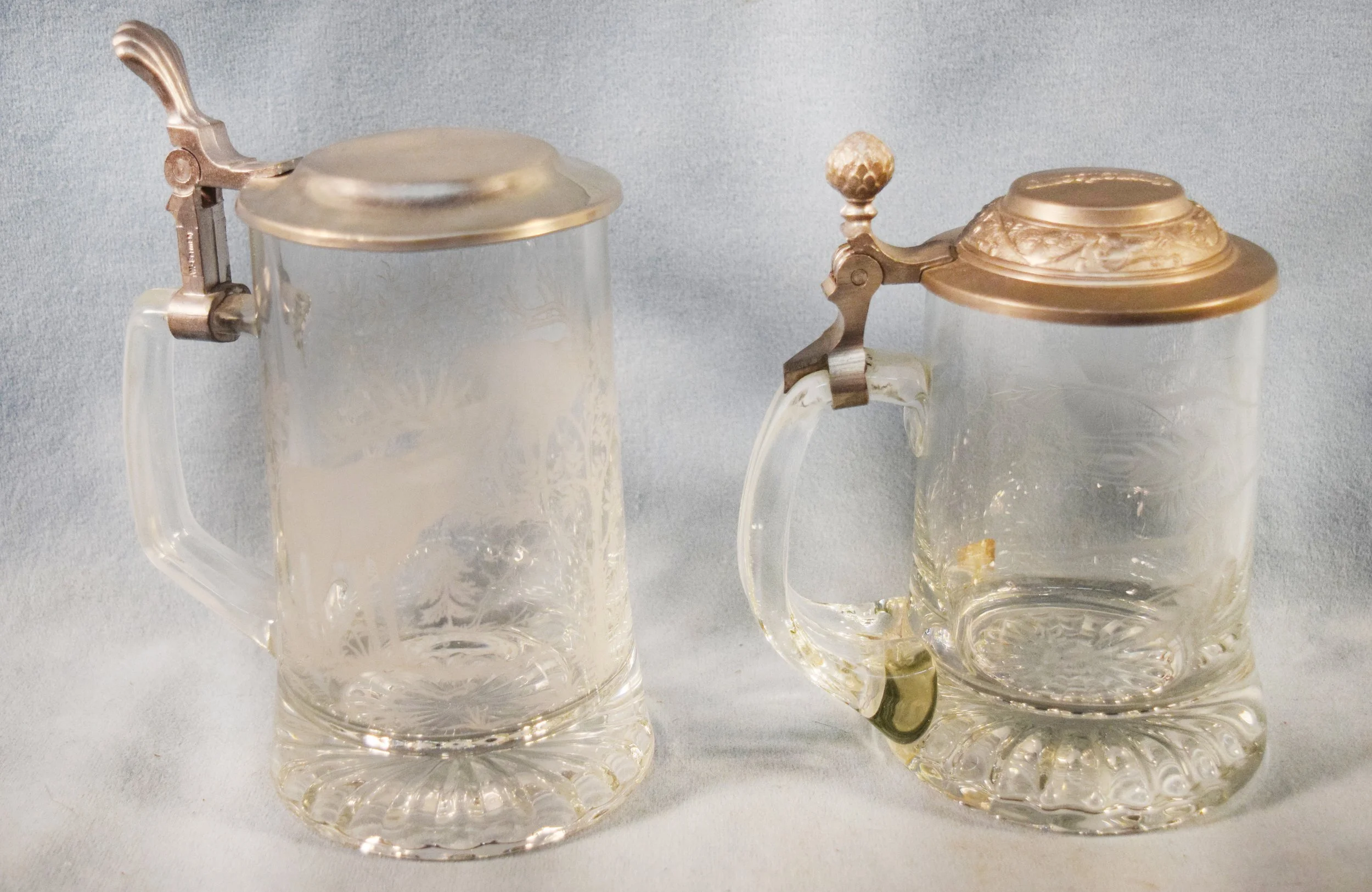 (2) German Steins: Etching of leaves, 5" tall, stamped Kronenbourg & Etching of elk, 6" tall, stamped W Germany.