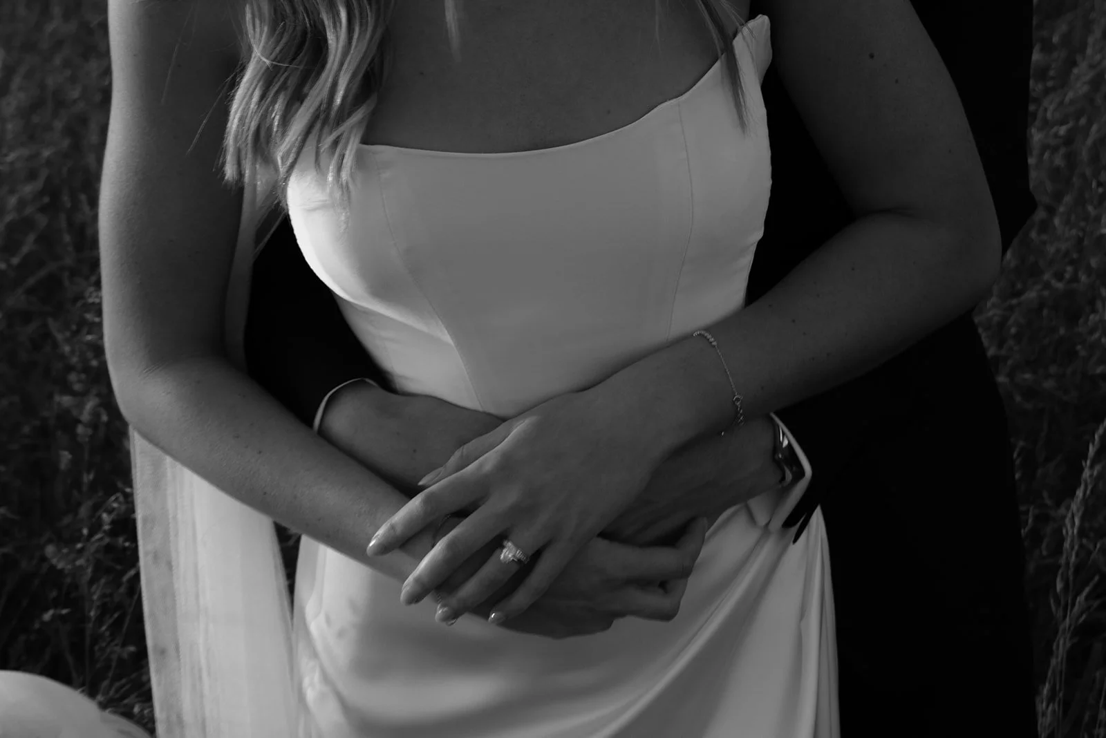 Black-and-white close-up of the bride’s hands and wedding ring against her gown at Goodstone Inn.