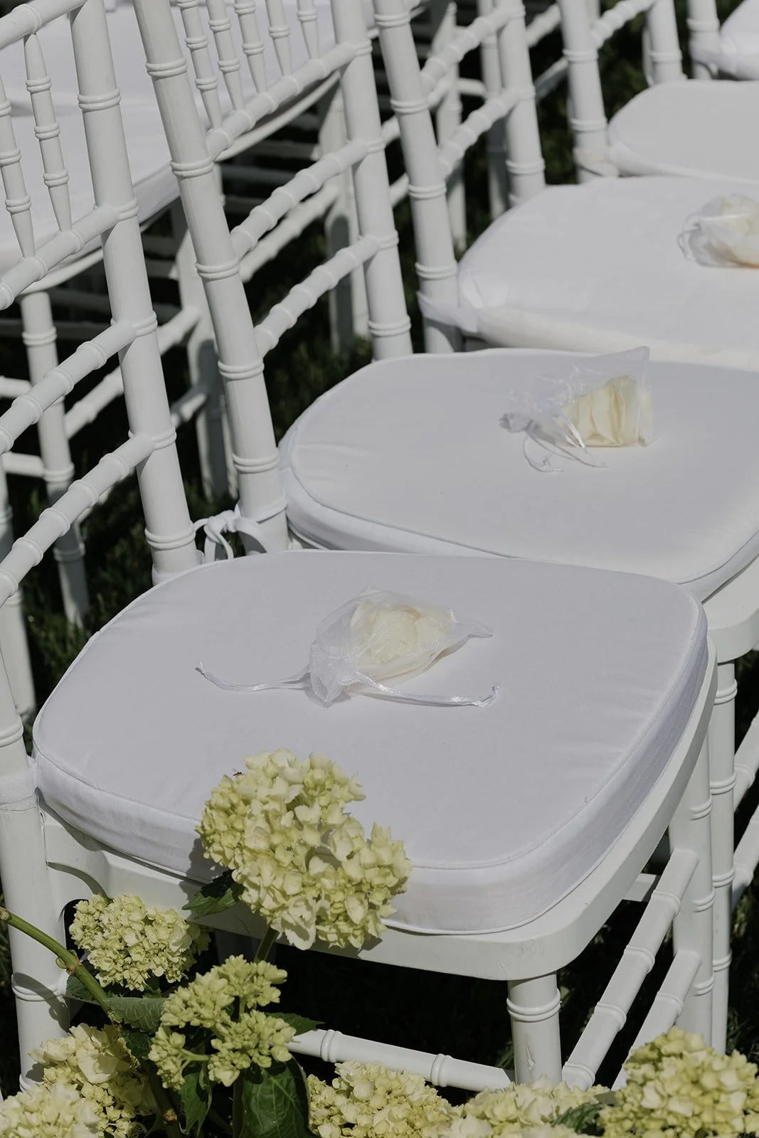 White outdoor ceremony chairs decorated with small ivory floral arrangements at Goodstone Inn in Virginia.