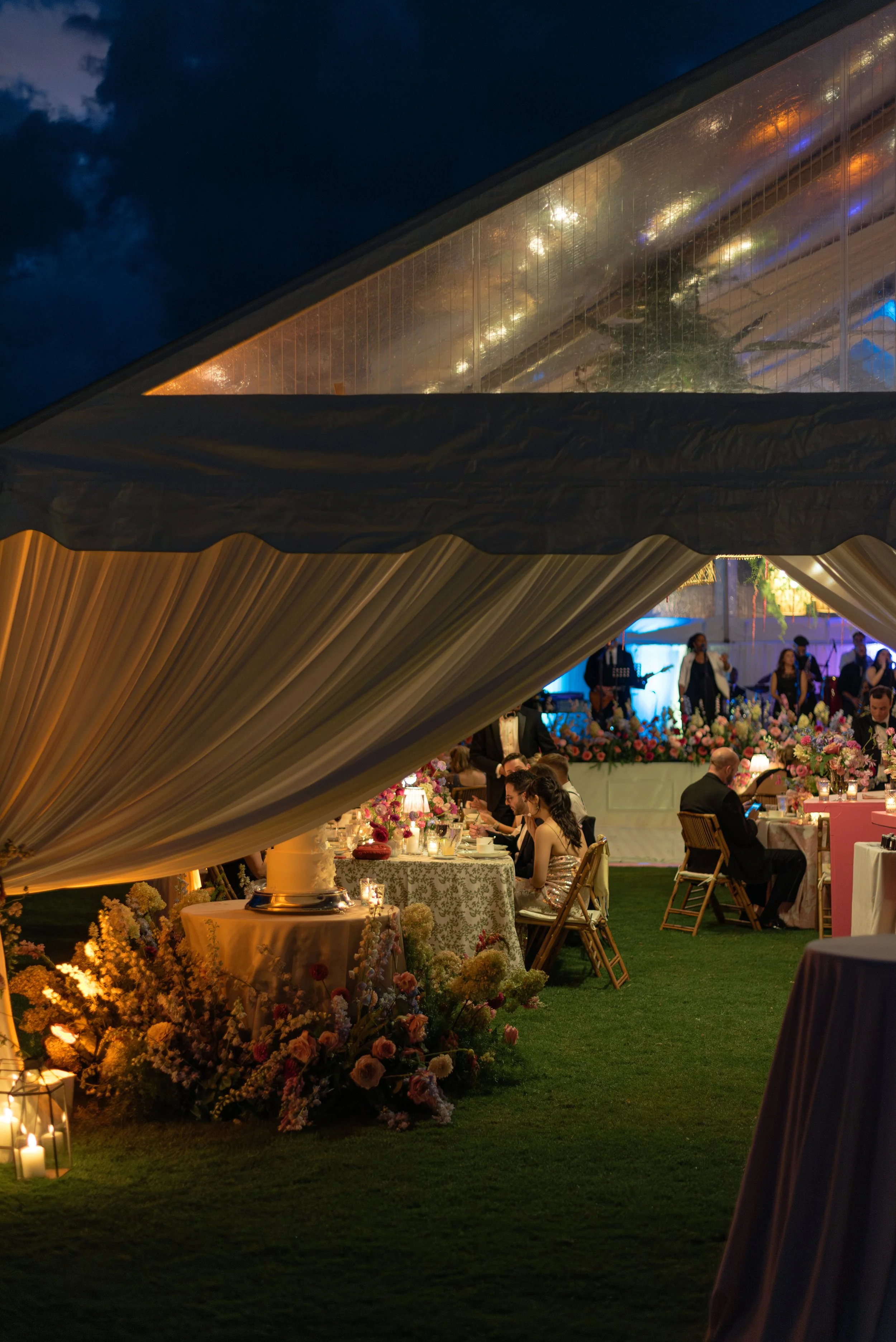 Flower-lined entrance opens into the glowing reception tent after dark at The Ocean Course.