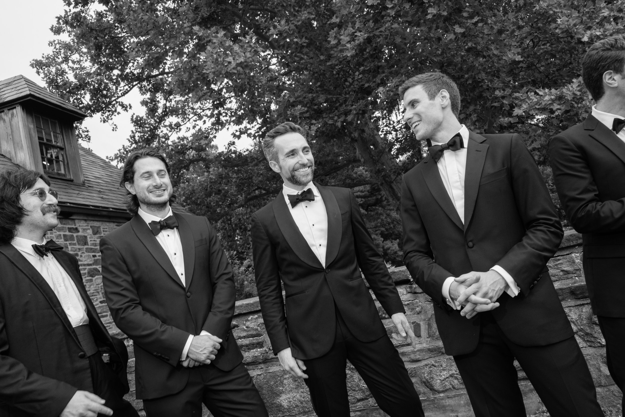Black-and-white portrait of Will laughing with his groomsmen before the ceremony at Blue Hill at Stone Barns.