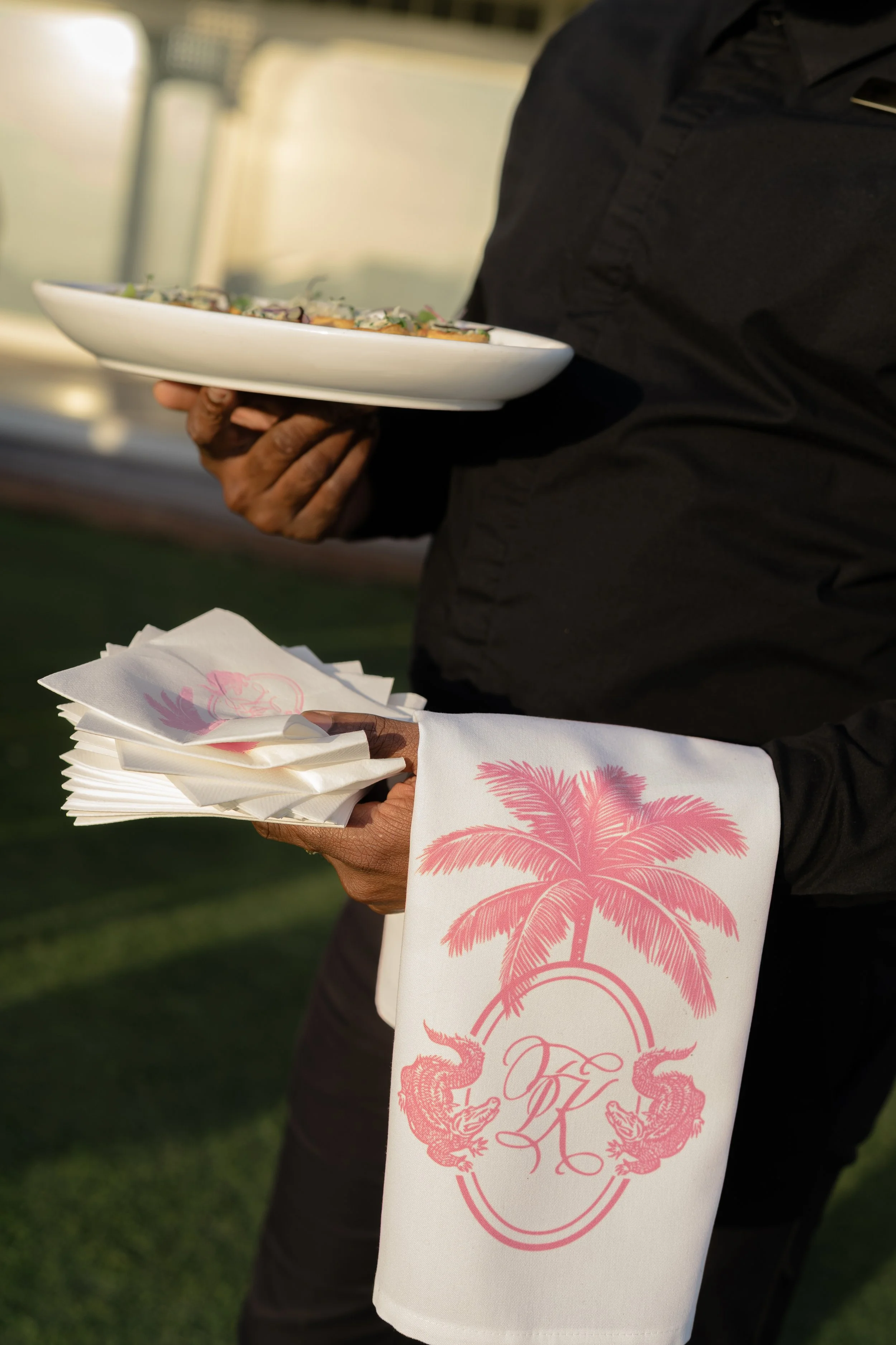 Server carries passed hors d’oeuvres with custom pink monogrammed cocktail napkins during the outdoor reception.