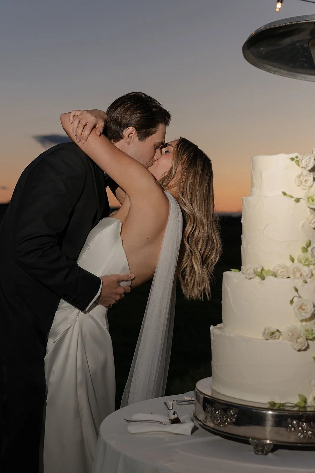 Bride and groom embracing beside their wedding cake during the reception at Goodstone Inn.