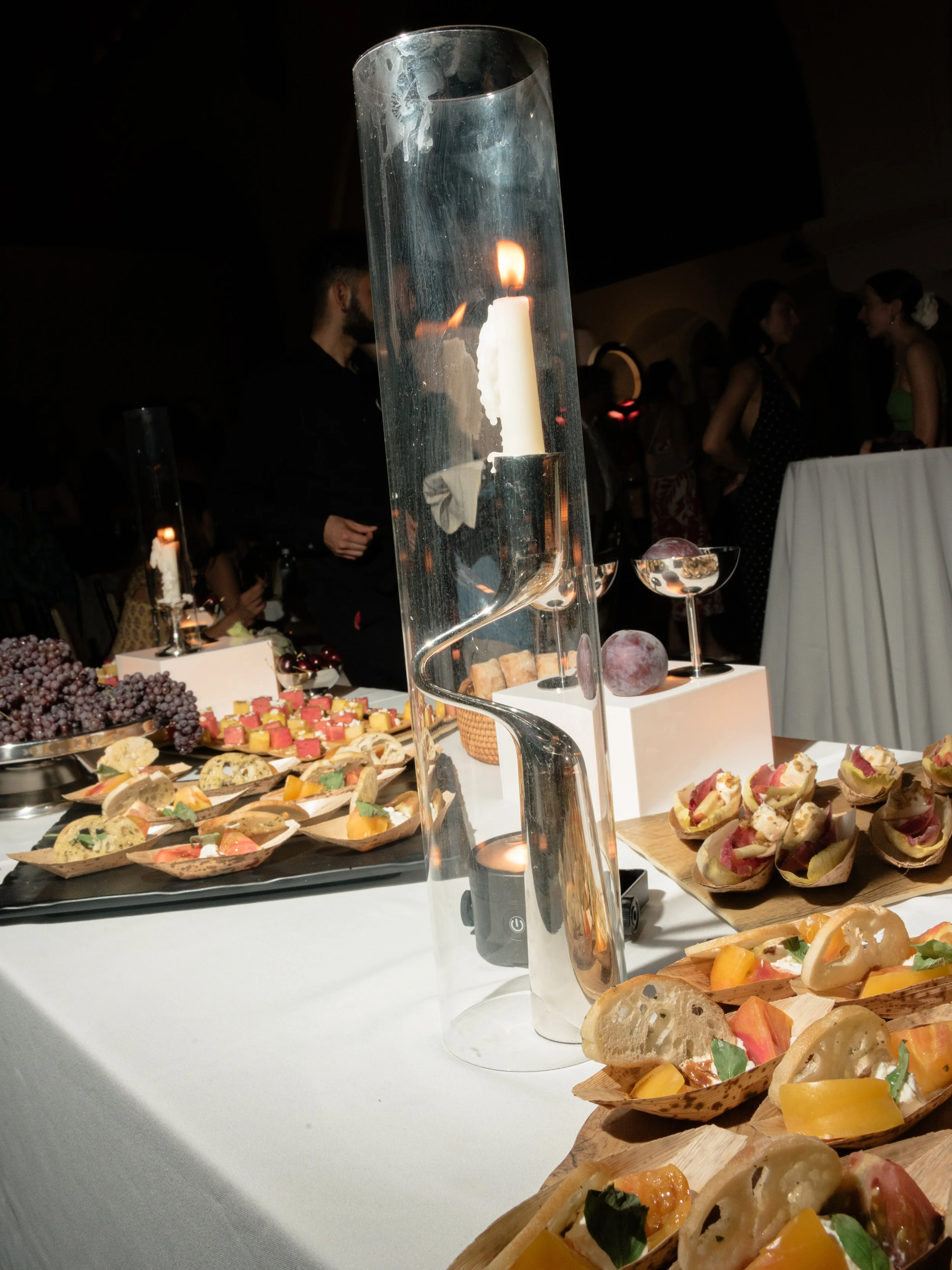 Artful late-night food display surrounded by candlelight with modern chrome taper candleholders in hurricane vases at The Abbey Inn & Spa.
