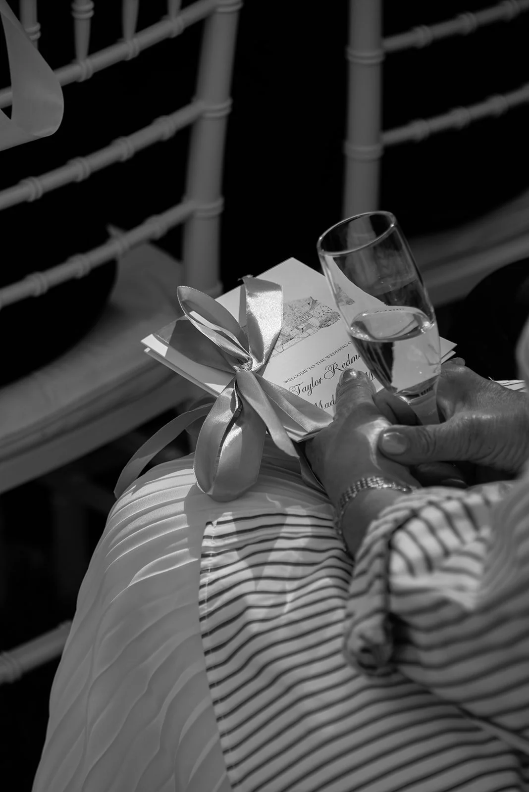 Close black-and-white detail of a wedding guest holding the ceremony program
