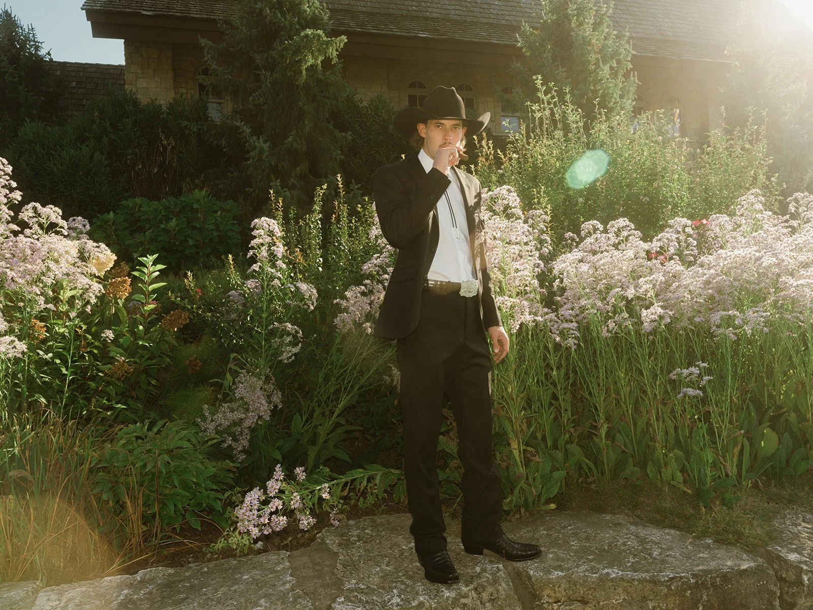 Groom standing among flowering gardens at Integrity Hills Stables in Ridgedale, Missouri, before a wedding celebration, photographed with natural light and an editorial storytelling approach.