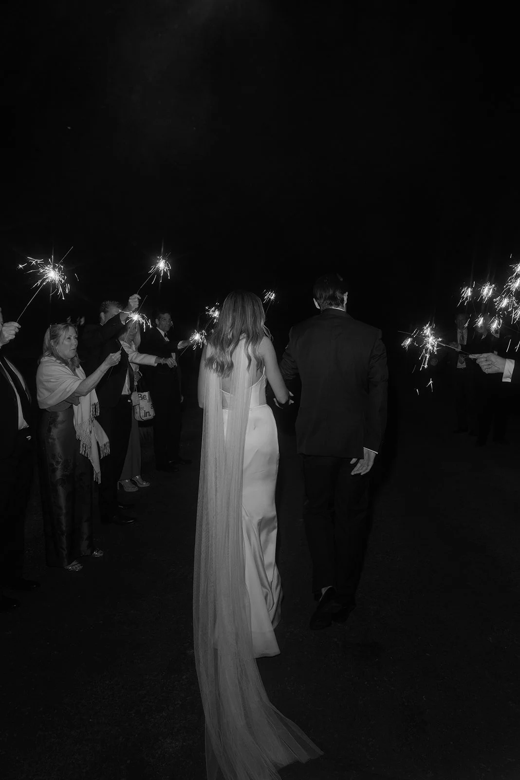 Black-and-white photograph of the bride and groom walking through a sparkler exit at Goodstone Inn.