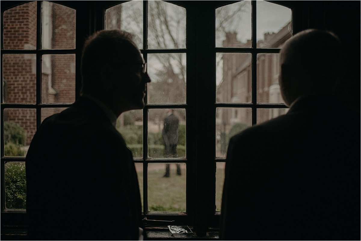 The bride and groom's fathers look through the windows to watch the first look of their son and daughter