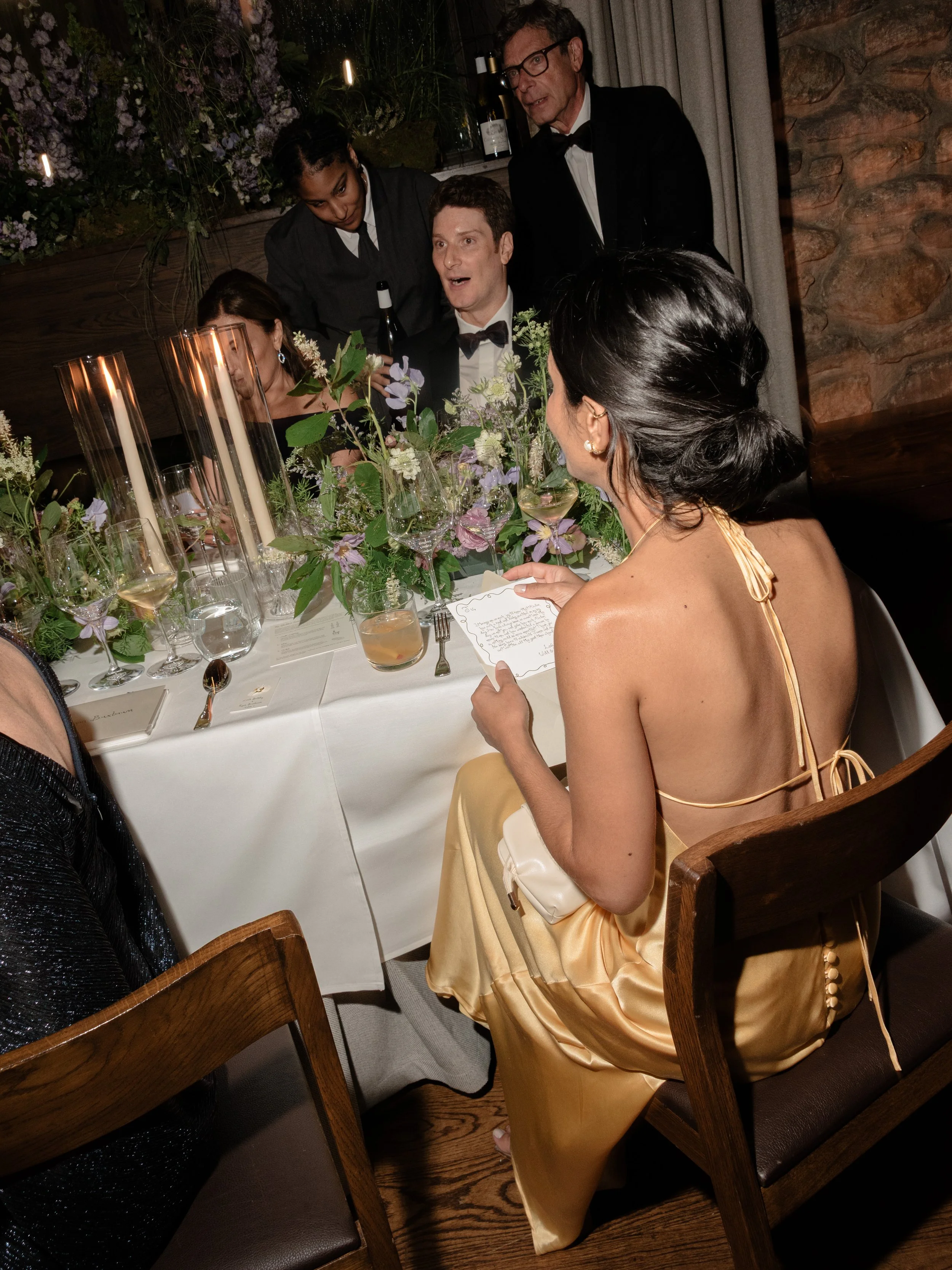 A bridesmaid seated among candlelight and flowers during the intimate wedding dinner at Blue Hill at Stone Barns.