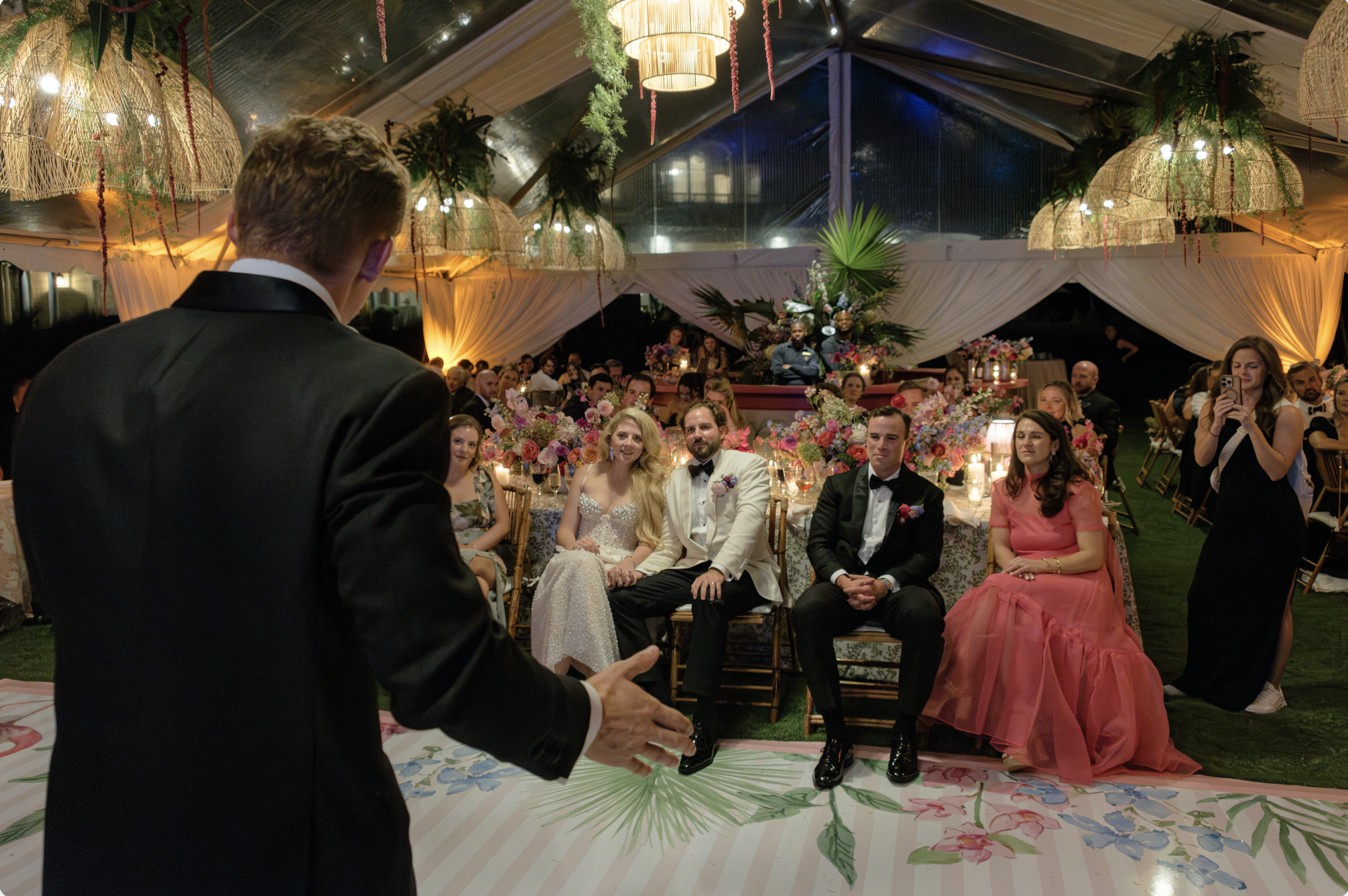 A wedding speaker addresses Katie, Trevor, and their guests inside the clear-top reception tent.