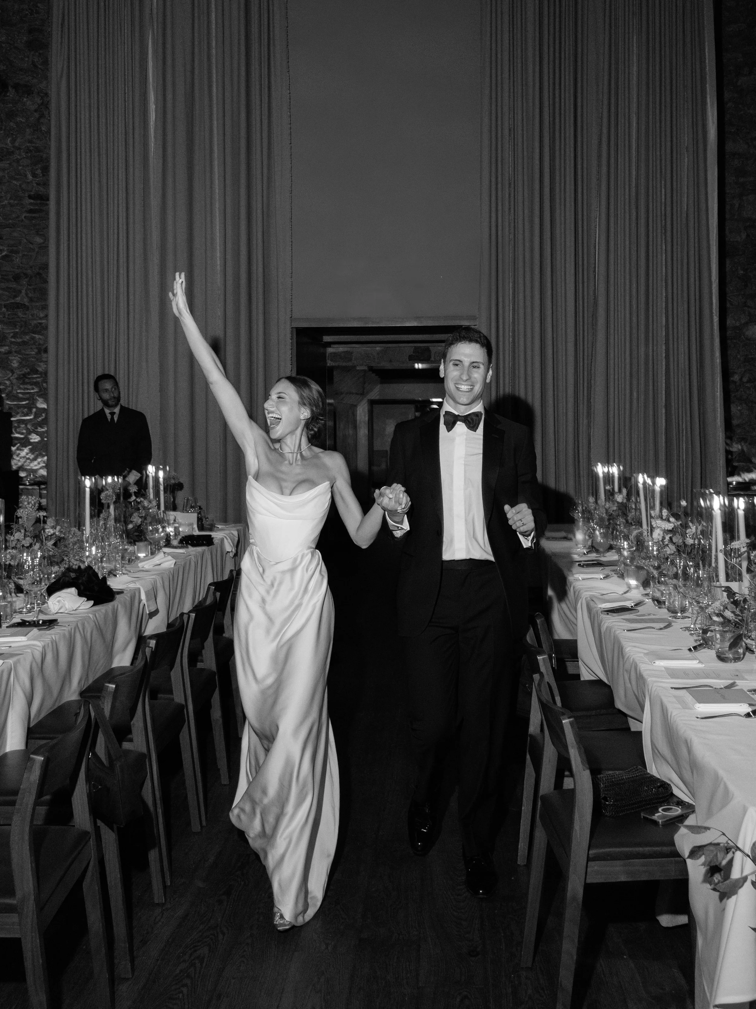 Black-and-white photograph of Jennie and Will entering the reception as guests celebrate around them.