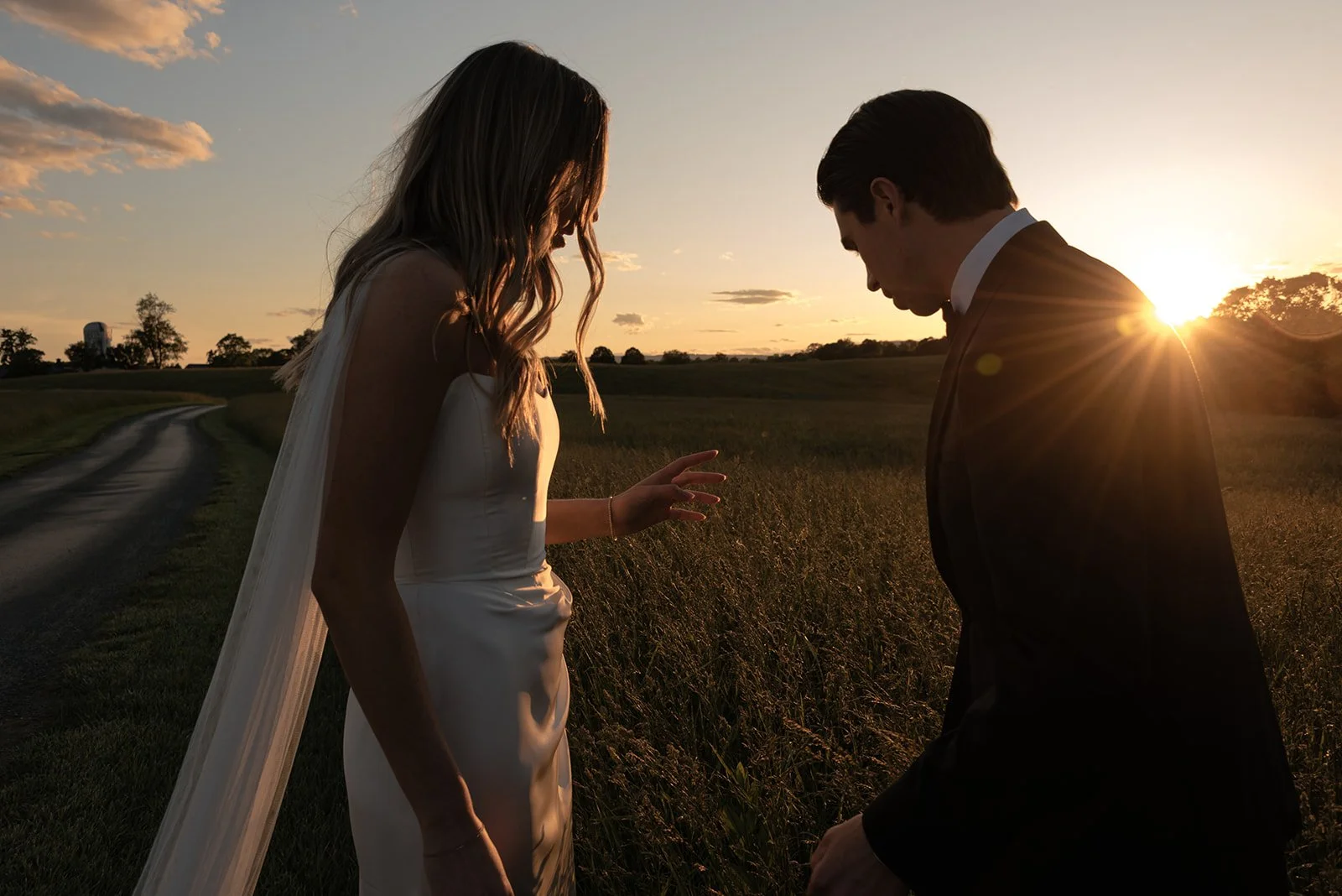 Bride and groom standing together with the setting sun behind them in the Hayfield at Goodstone Inn.