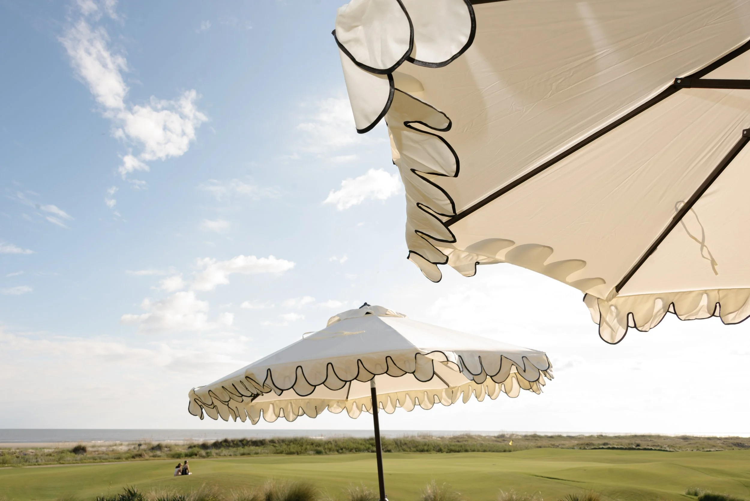 White scalloped umbrellas with black trim overlook the coastal golf course and ocean at The Ocean Course on Kiawah Island.