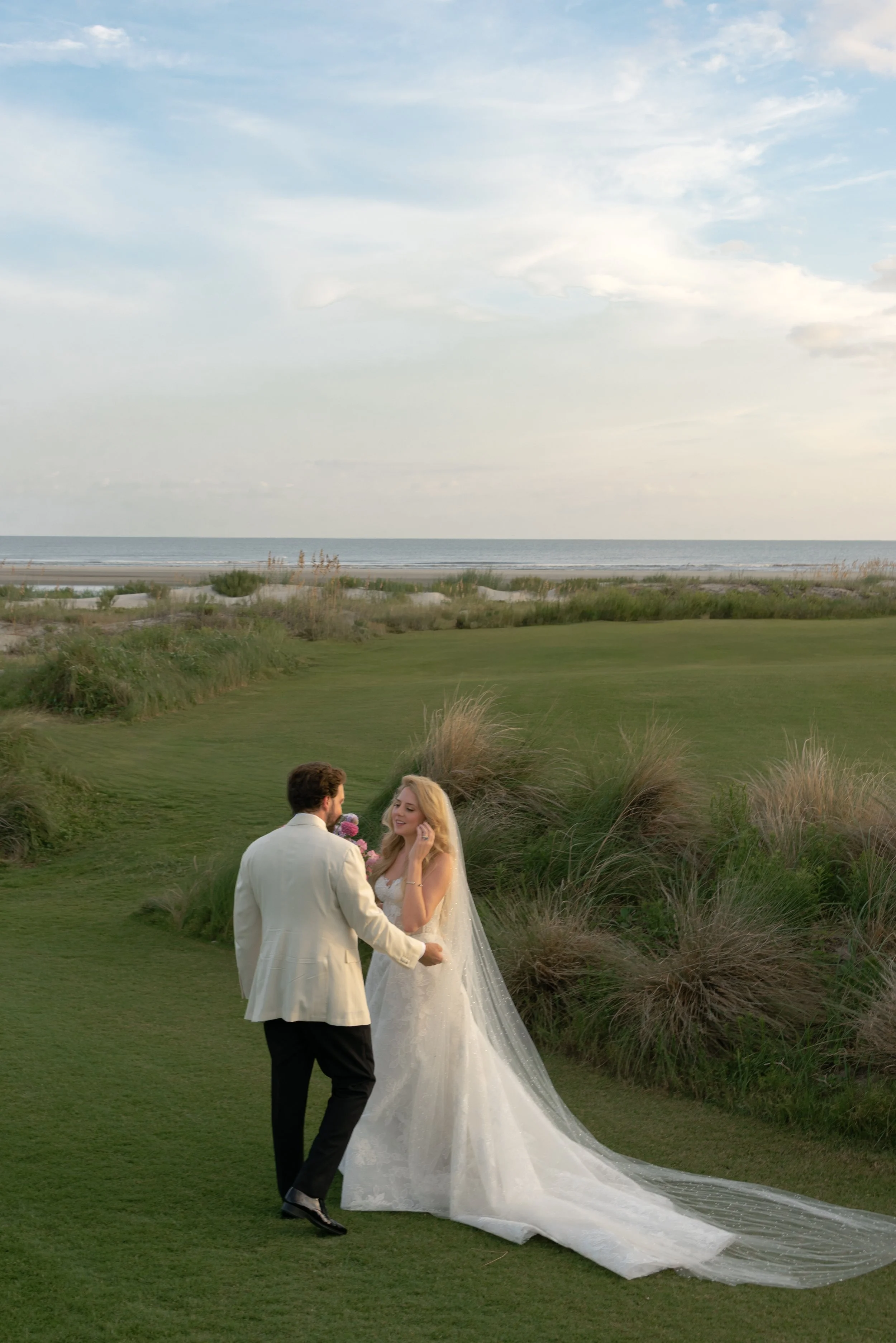 The bride and groom stand together in the expansive coastal landscape at The Ocean Course on Kiawah Island.
