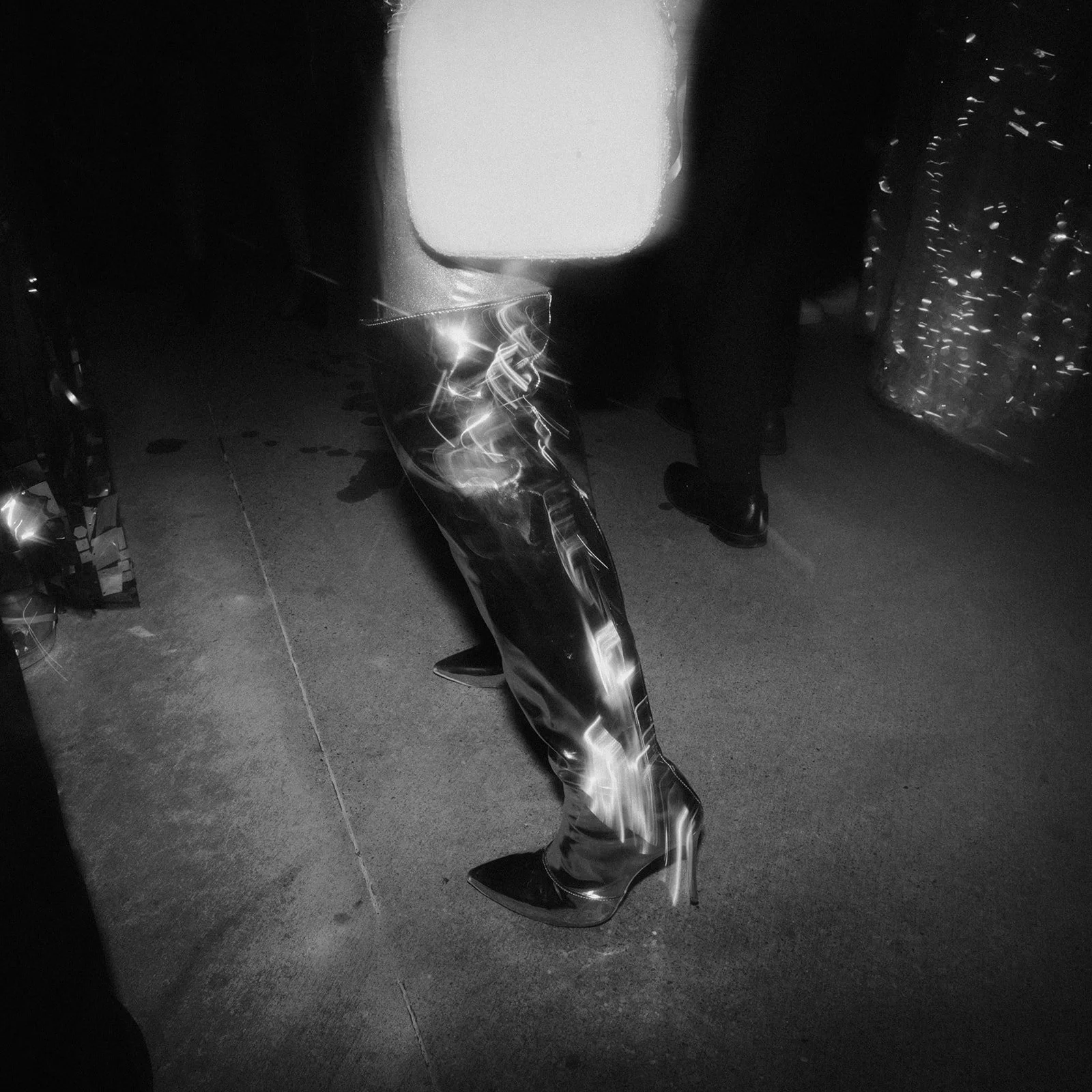 Black and white editorial photograph of a fashion-forward detail from a celebration, highlighting texture, movement, and unconventional artistic composition.