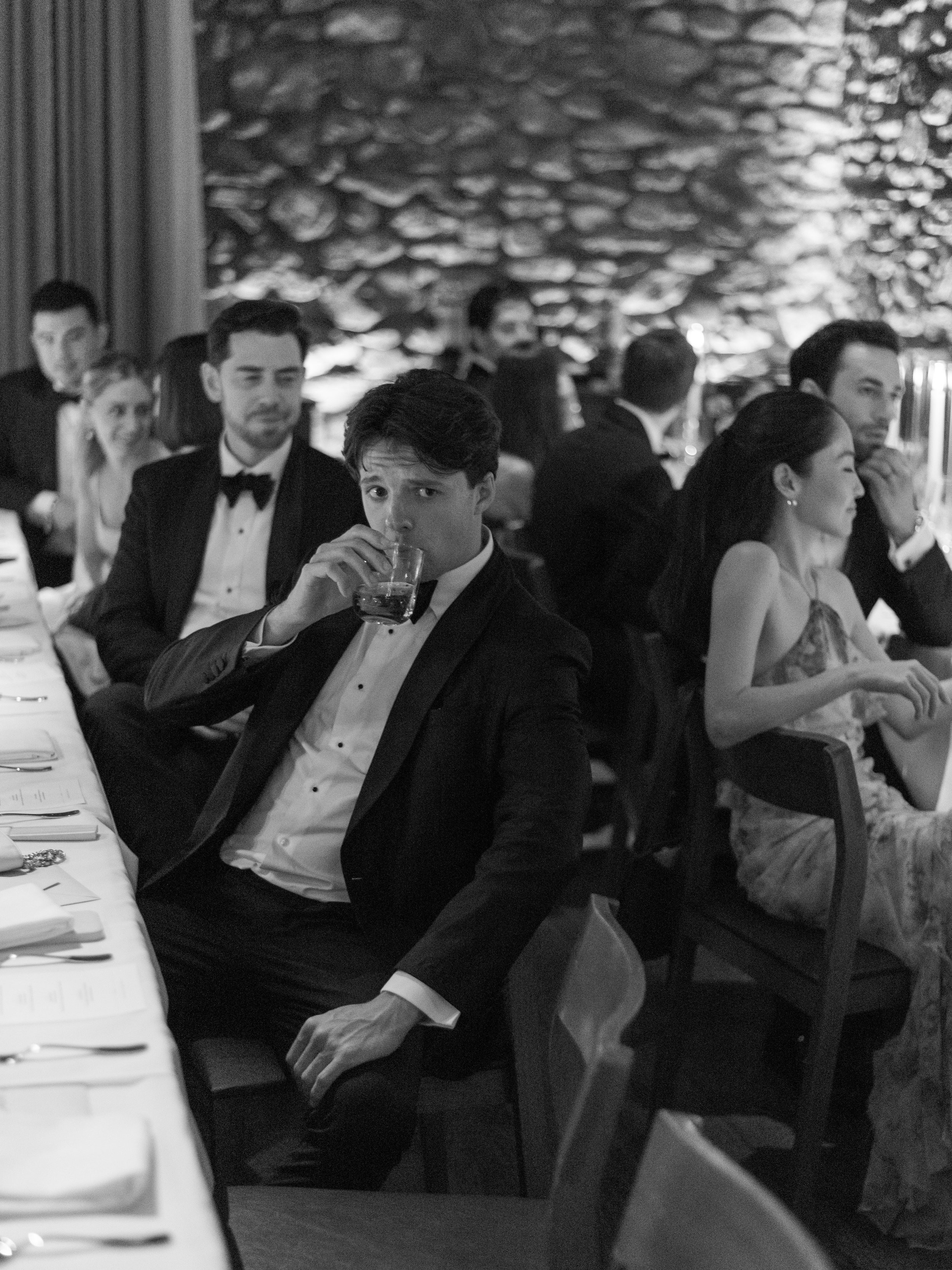 Black-and-white view of guests seated around the long dinner table at Blue Hill at Stone Barns.
