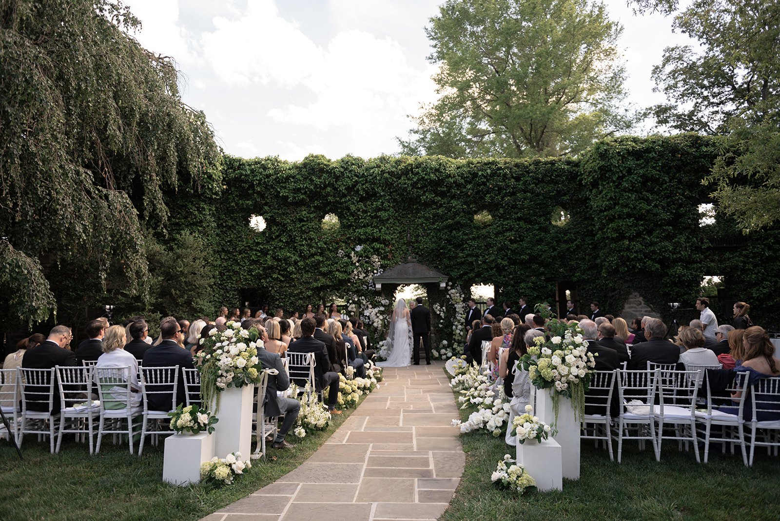 Bride and groom standing at the Ivy Wall ceremony surrounded by wedding guests at Goodstone Inn.