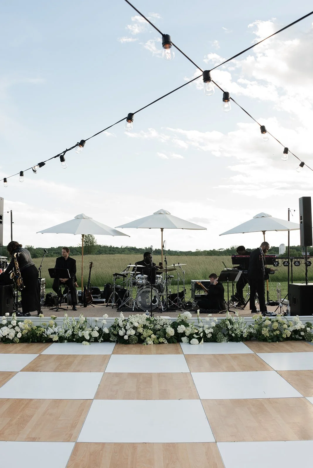 String lights stretching over an outdoor checkerboard dance floor beneath a blue spring sky at Goodstone Inn.