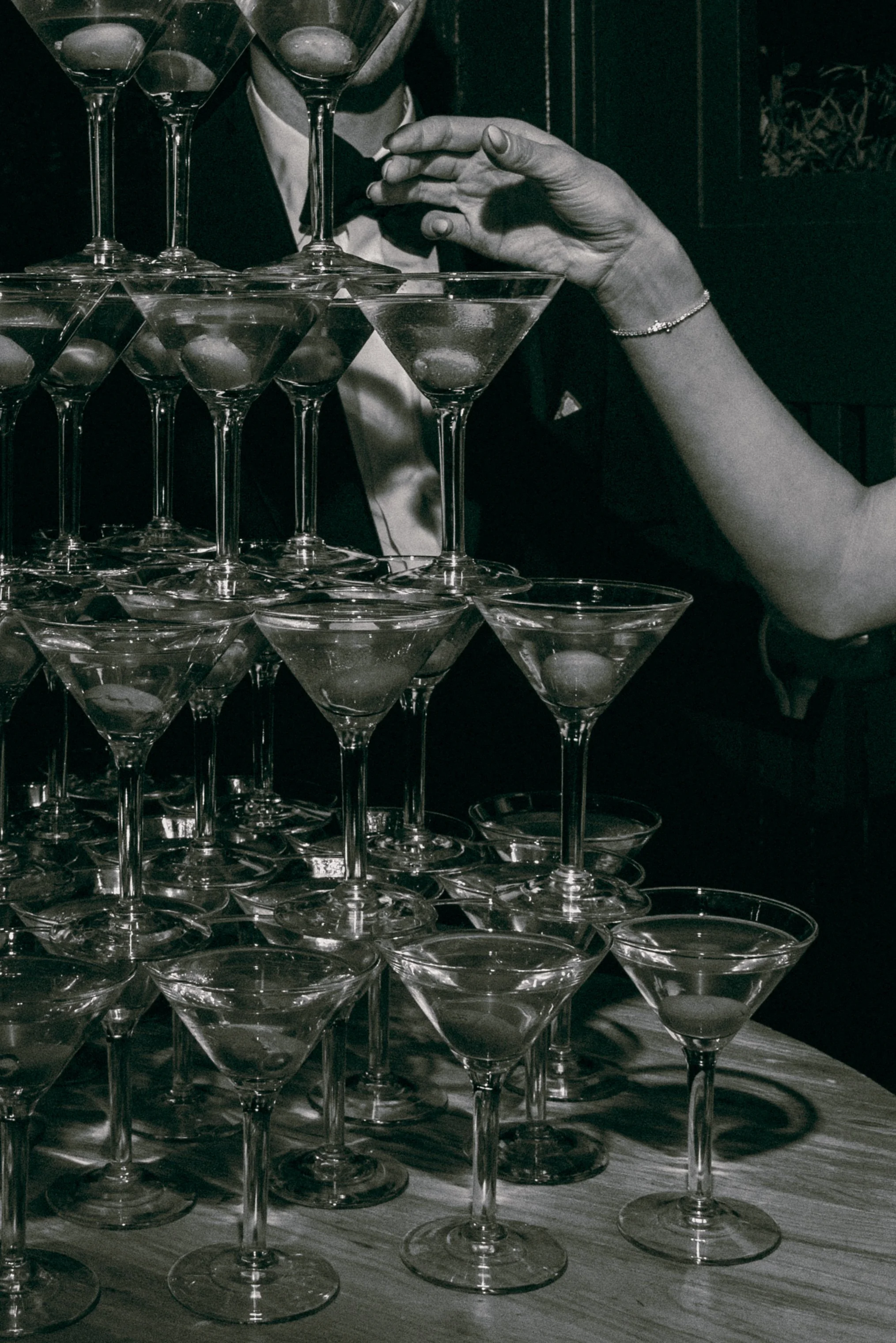 Black and white editorial photograph of a martini tower detail during a luxury wedding reception.