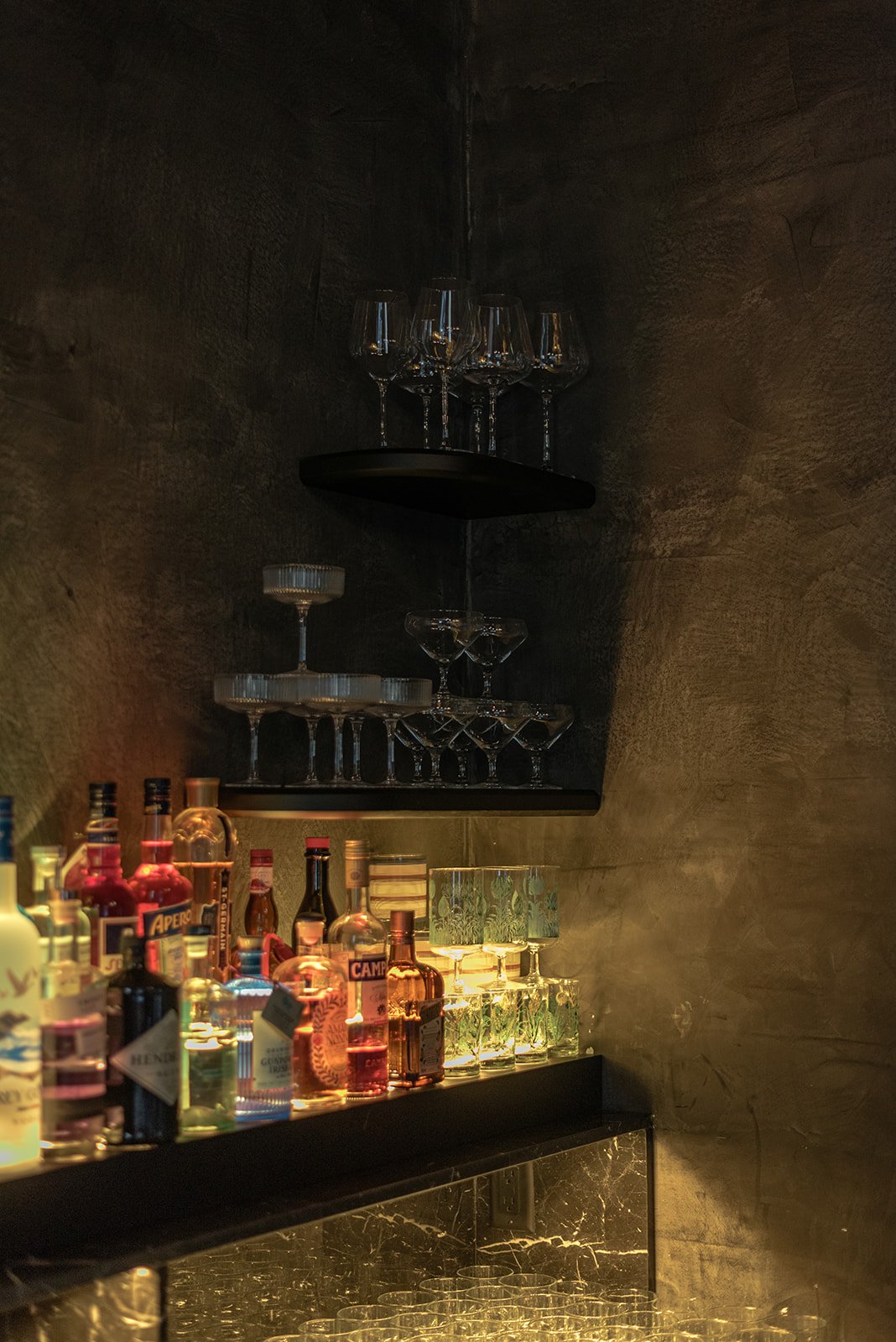 Editorial photograph of a curated cocktail bar display with colorful bottles and glassware, showcasing hospitality design and intentional event details at Sardis Hills in Chattahoochee Hills.