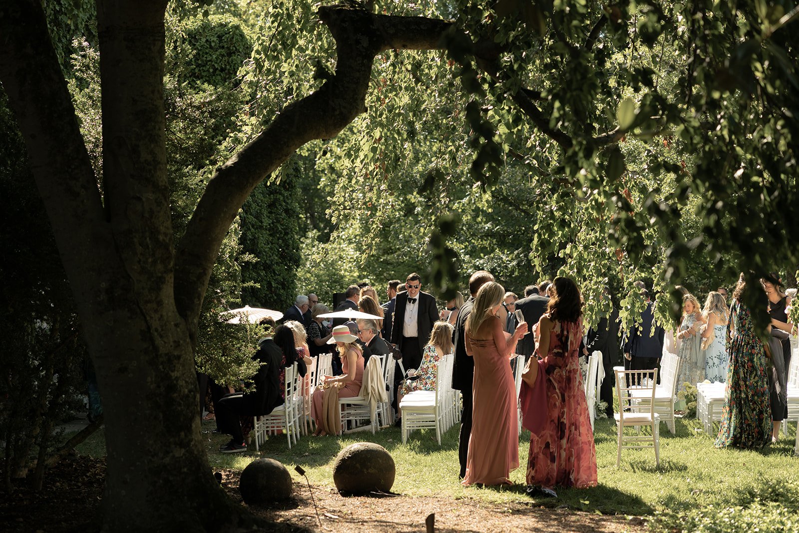 Wedding guests mingling beneath a large tree during outdoor cocktail hour at Goodstone Inn.