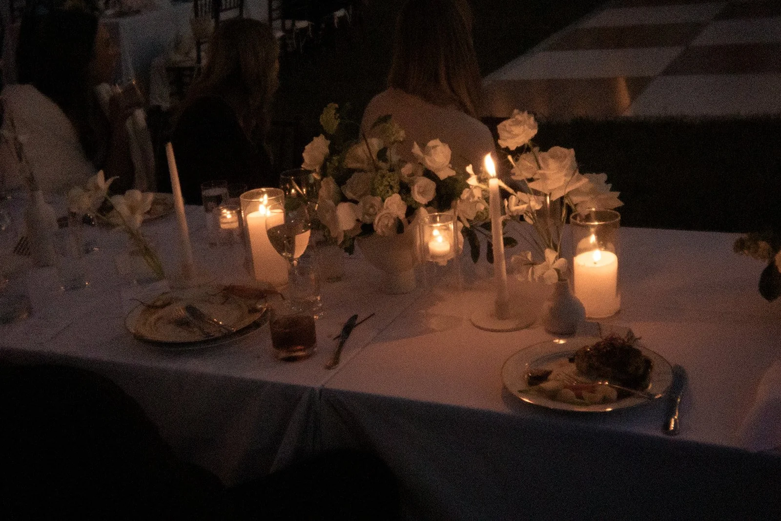 Candlelit outdoor reception table with ivory flowers and glassware at Goodstone Inn.
