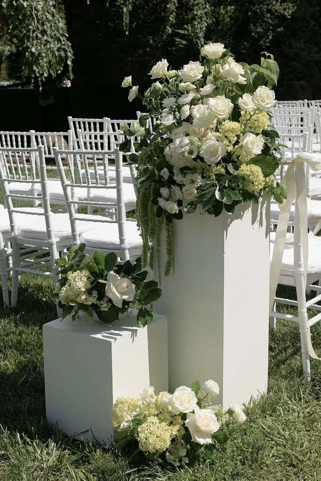 White ceremony pedestal topped with ivory garden flowers beside rows of chairs at Goodstone Inn.