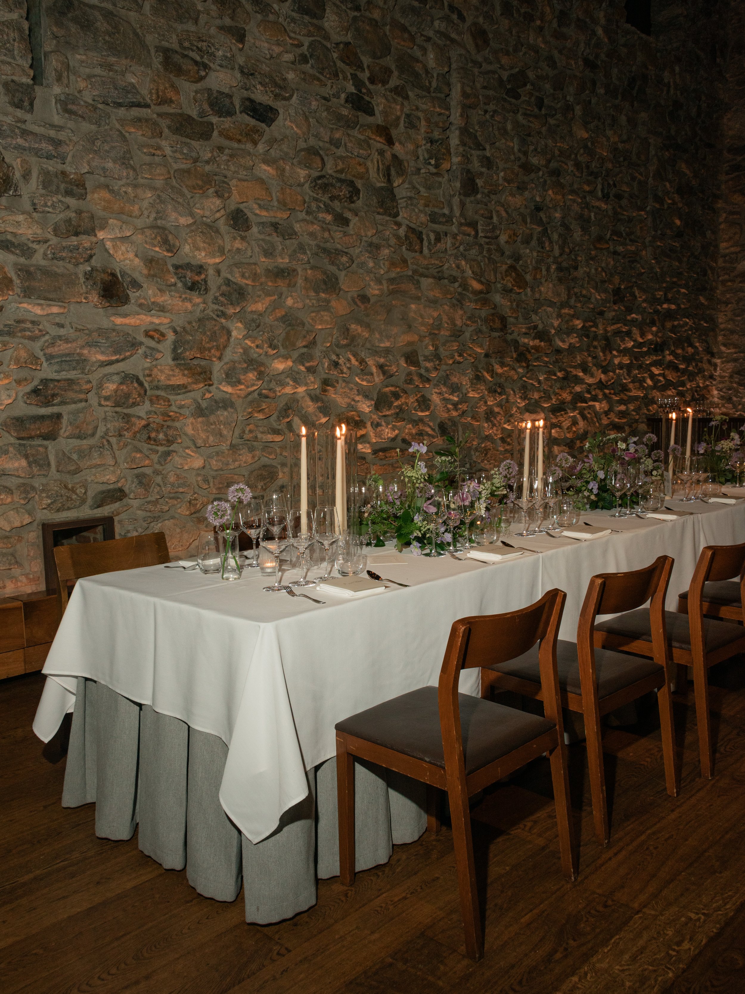 Long reception table set against the historic stone walls of Blue Hill at Stone Barns.