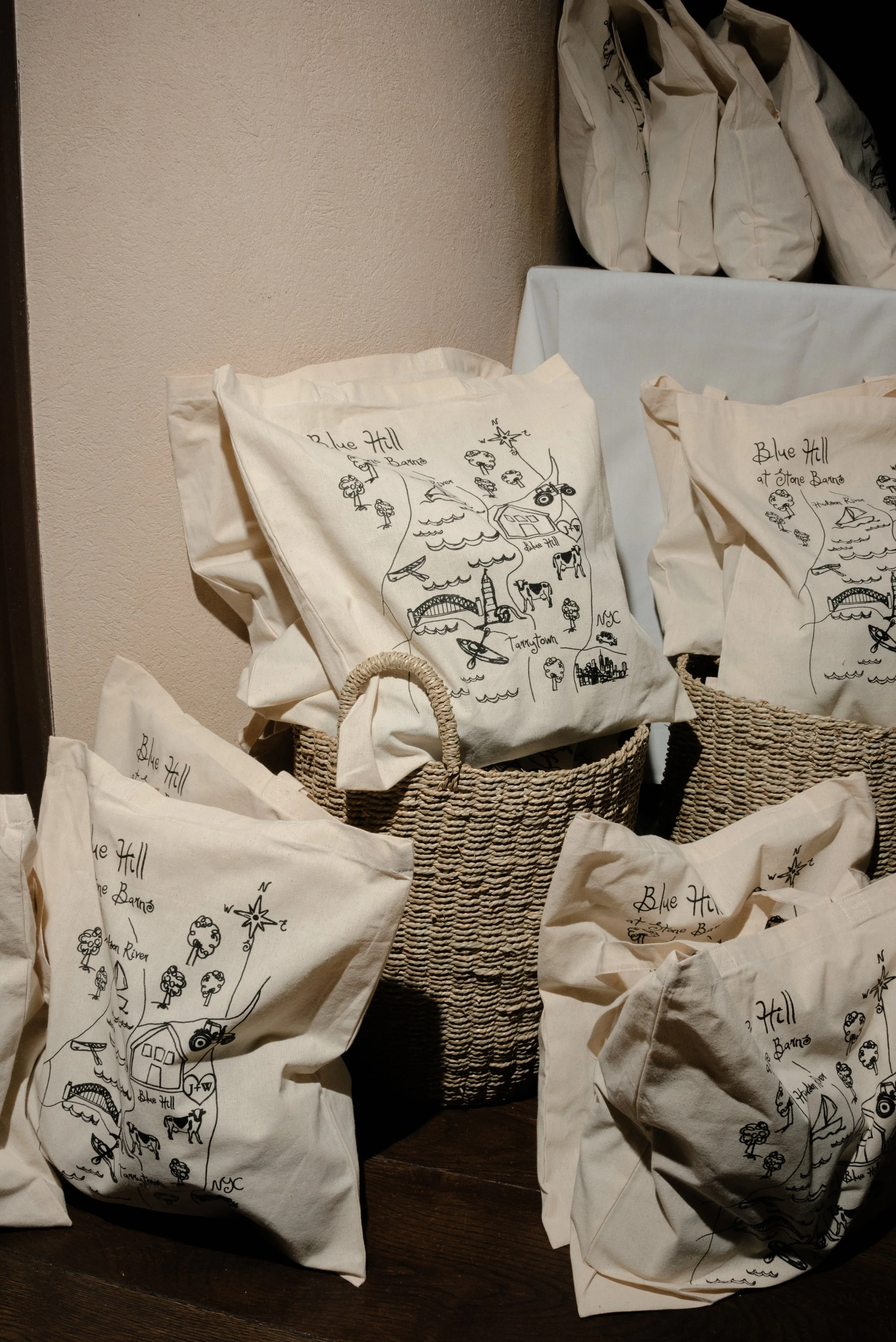 Illustrated custom tote bags displayed as guest favors during Jennie and Will’s wedding weekend.
