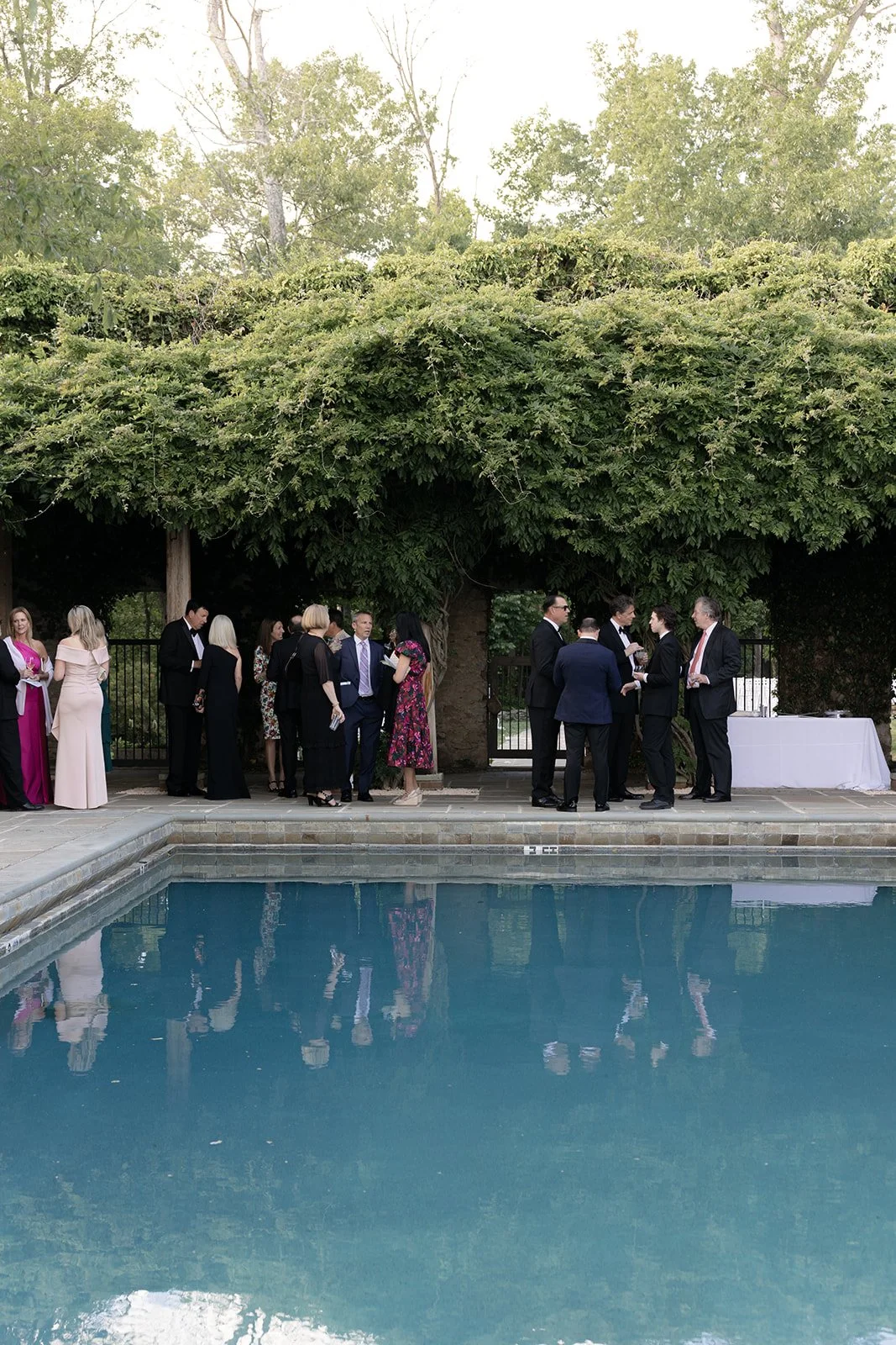 Wedding guests mingling beside the pool during cocktail hour at Goodstone Inn.