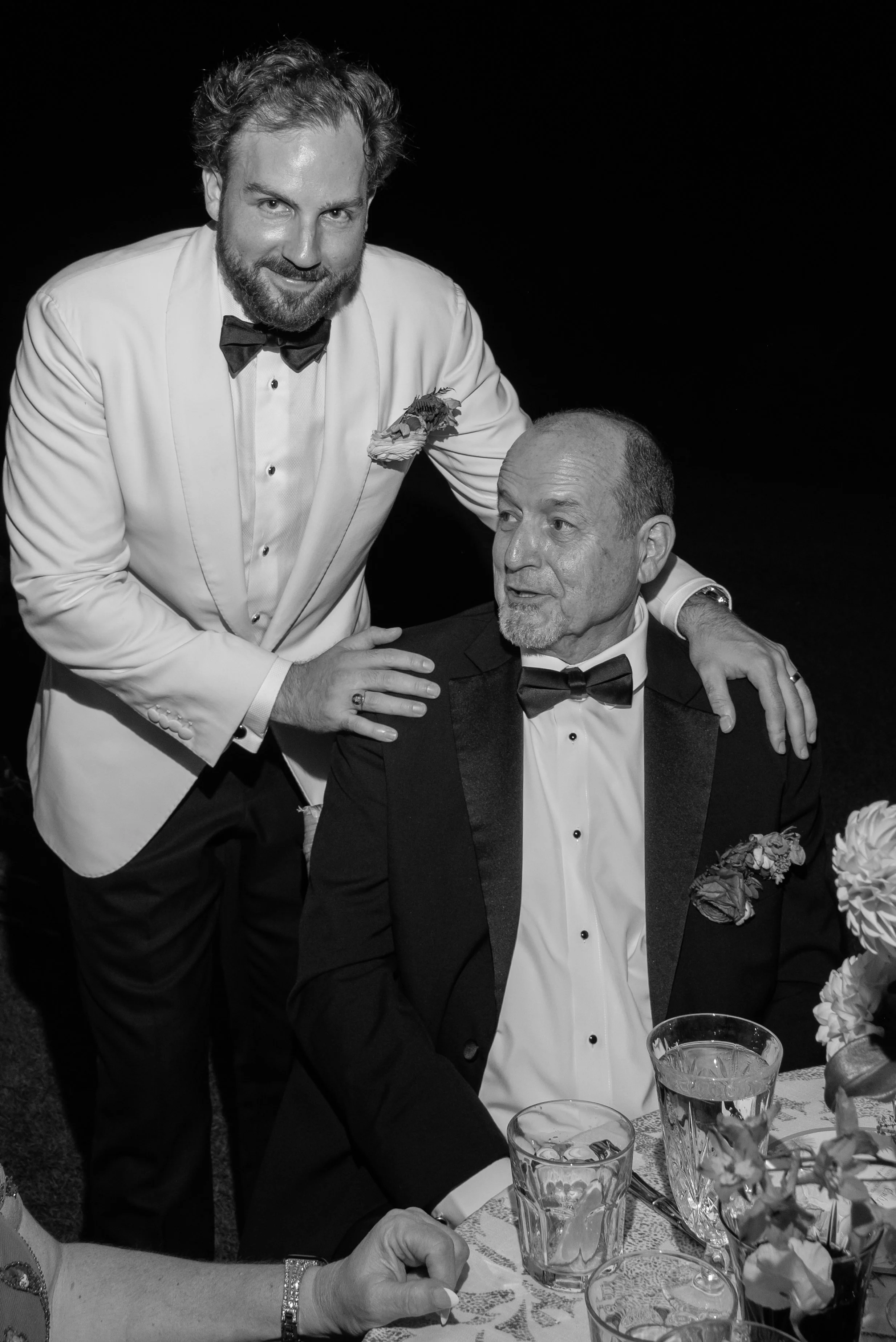 Black-and-white photograph of Trevor standing beside his father during the wedding reception.