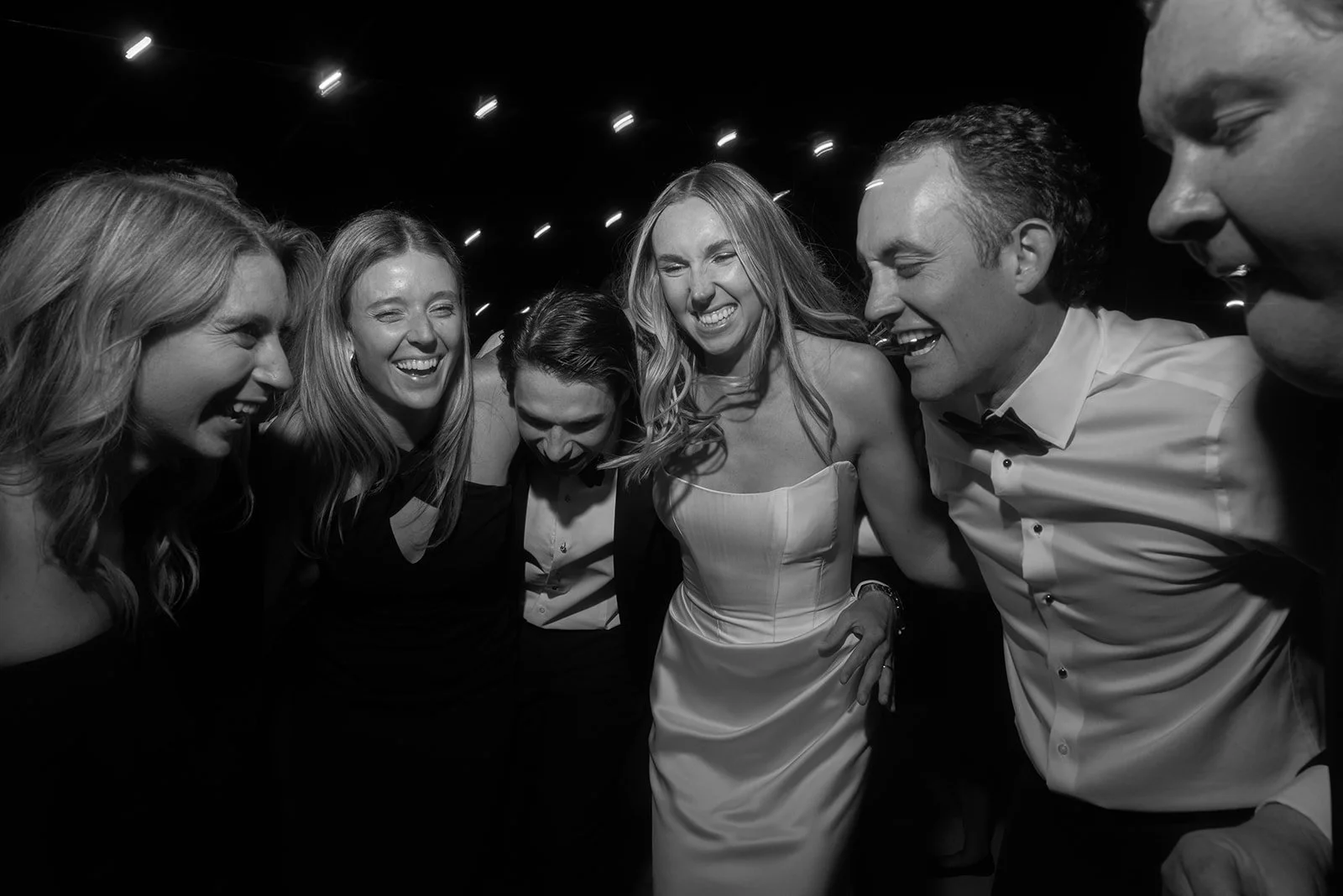 Black-and-white photograph of wedding guests laughing together on the dance floor at Goodstone Inn.